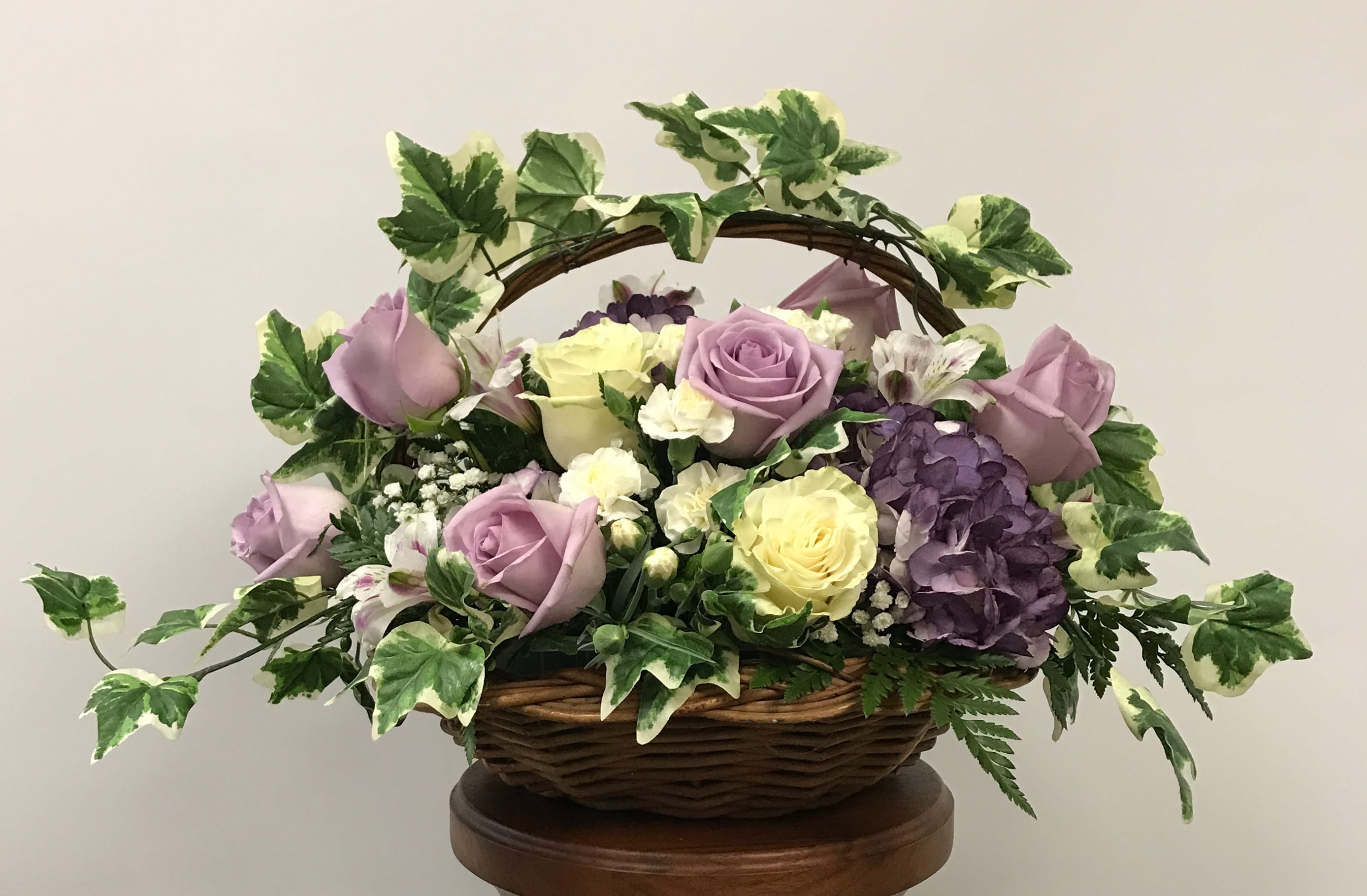 A Basket of Care - This beautiful basket of purple and white flowers is a wonderful way to express how much you care.  ***The deluxe version is pictured***  Brilliant flowers SUCH AS purple hydrangea, lavender roses, white miniature carnations, alstroemeria, and gypsophila are arranged with ivy and more in a basket. Minor substitutions may be necessary due to availability.  Orientation: All-Around    N211-1 