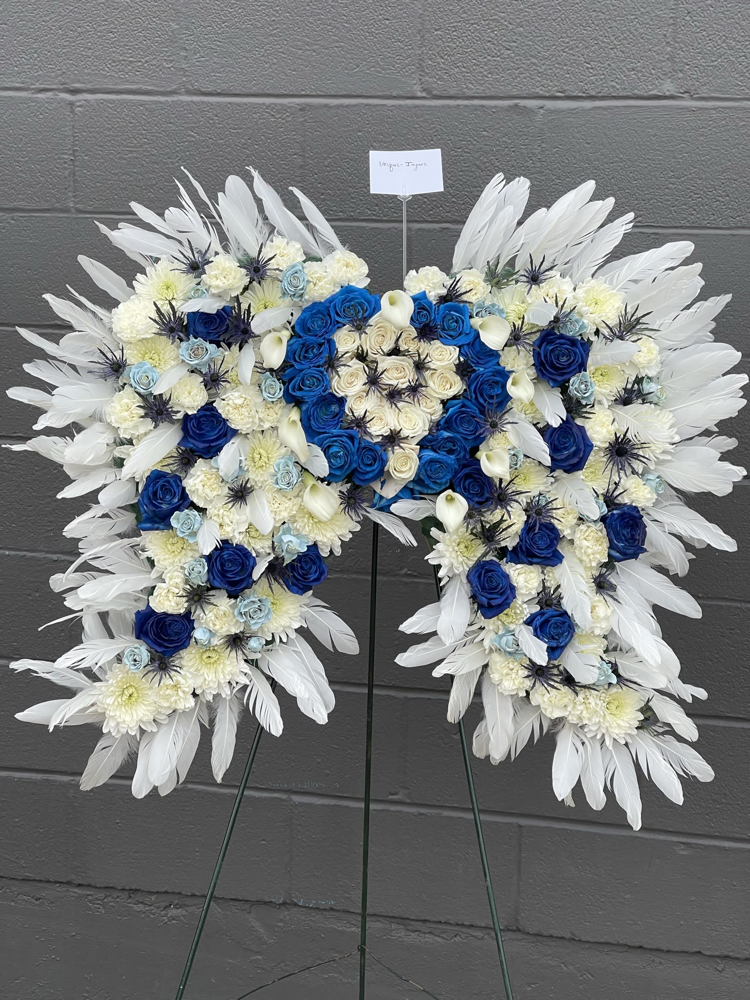 The Royal Heavens Angel Wings  - These beautiful wings are a great size they are filled with roses, spray roses, mums and a variety of filler flowers. These wings are carefully decorated with white feathers all over the wings. This makes a beautiful statement 