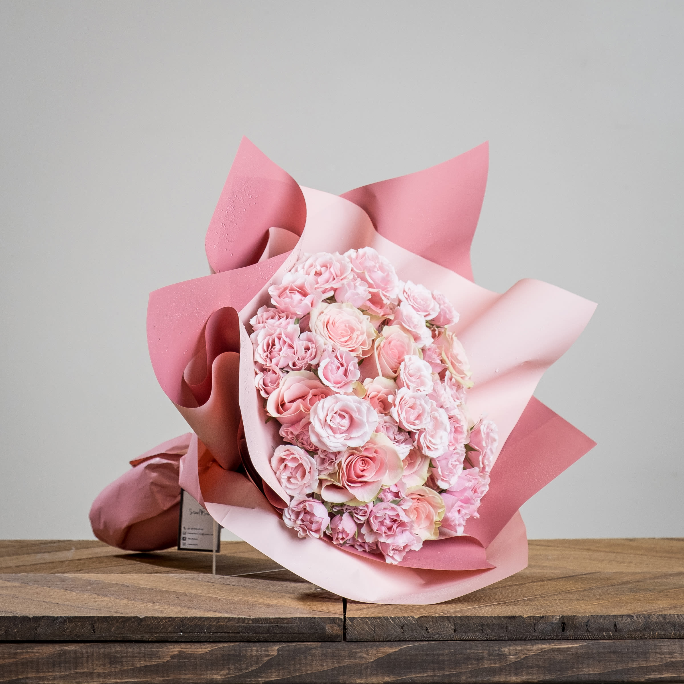Pretty in Pink Wrap Bouquet  - A flirty and luxurious soft pink bouquet features eighteen roses surrounded by delicate blooms of majolica spray roses that's all wrapped up inside layers of gorgeous pink paper.Give your special Valentine a gift they'll always cherish and remember for years to come. 
