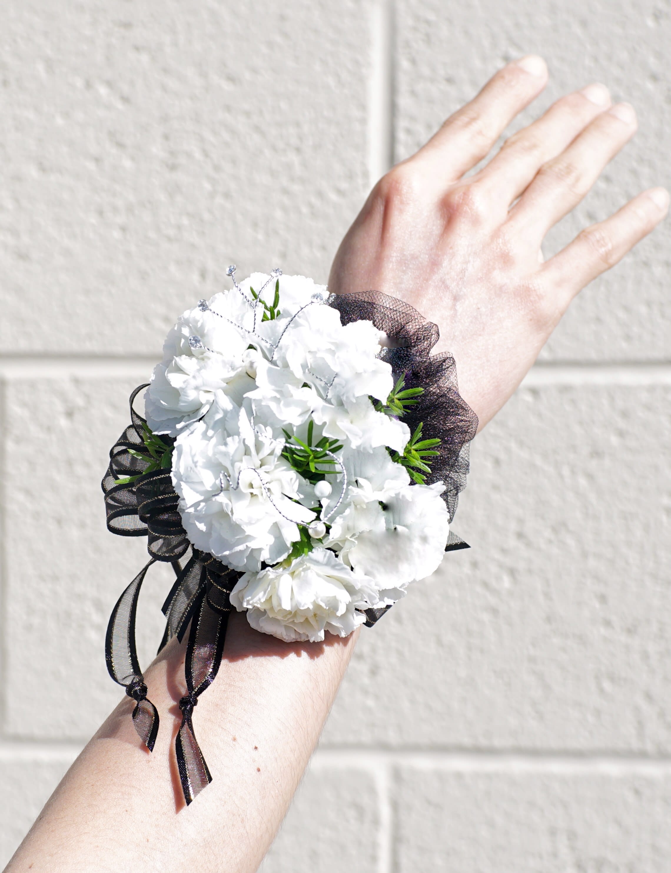 Wrist Corsage 27 - Wrist corsage with carnation and accents. CUSTOMER CAN CHOOSE ANY COLOR. STANDARD: WRIST CORSAGE DELUXE: WRIST CORSAGE + BOUTONNIERE
