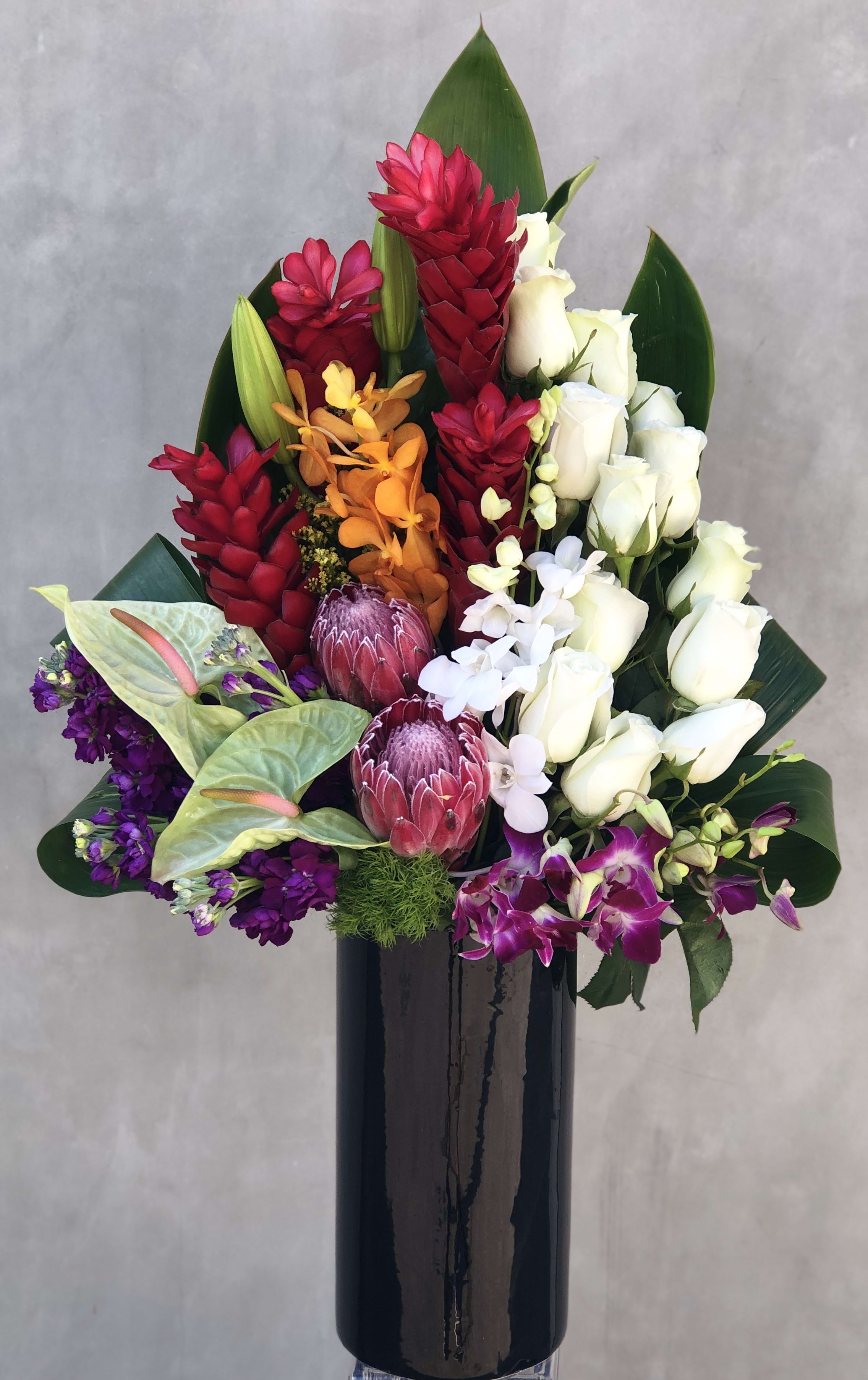 Tropical island Tropical island - Beautiful and bright arrangement, filled with red ginger, roses, orchids, anthuriums, proteas and much more. Arrange in a tall vase.