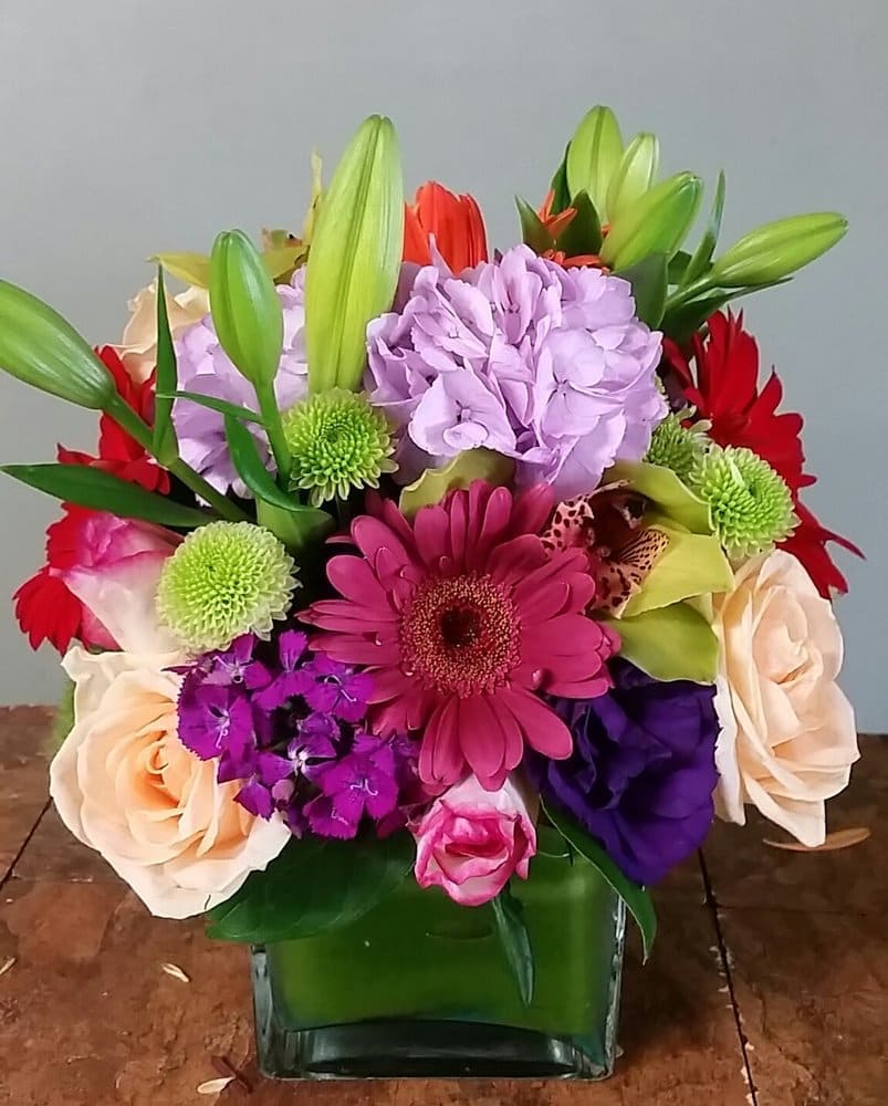Delightful Daisy Delightful Daisy - variety of mix flowers, lilies, daisies, rose, and much more arranged in a square vase.