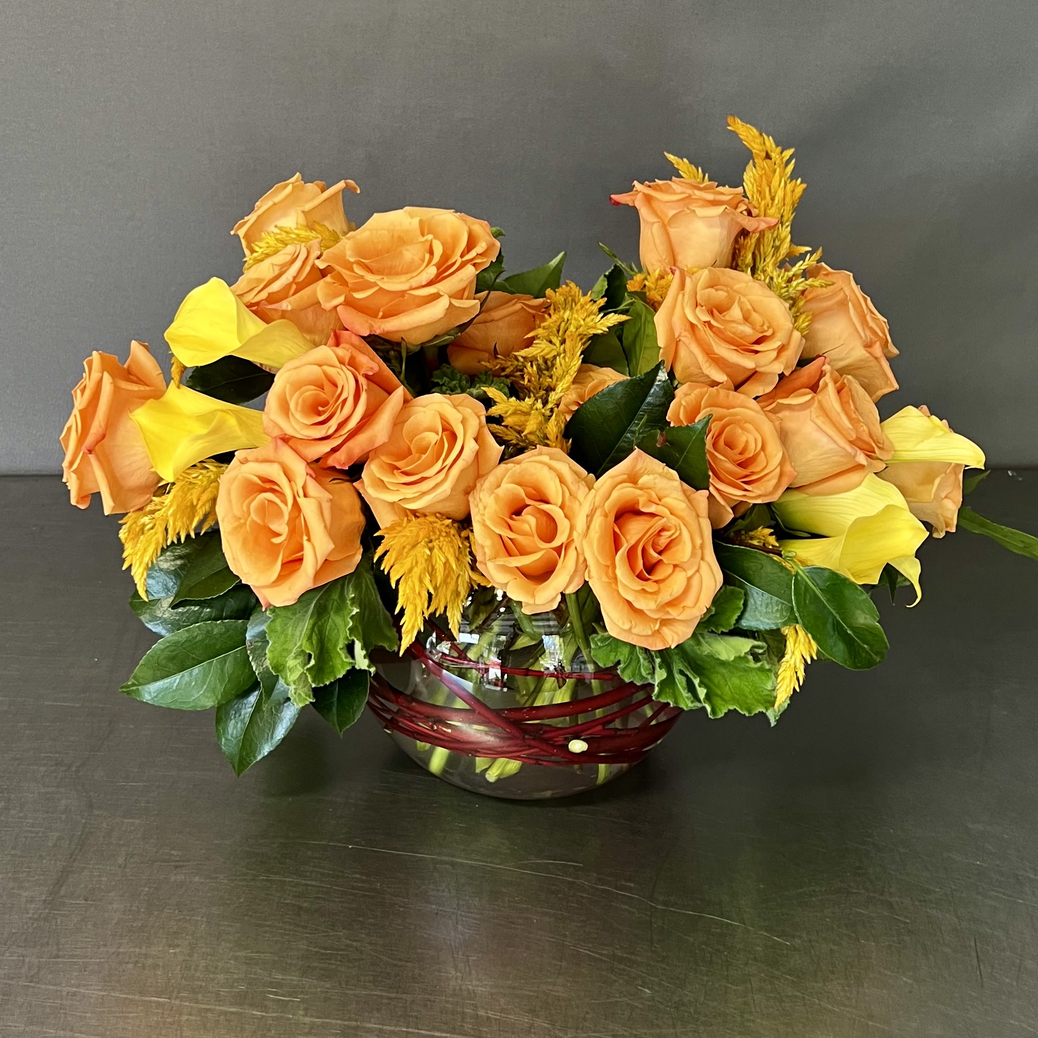 ORANGE AND YELLOW - This arrangement is a showstopper that has Roses and seasonal flowers arranged together in an 8&quot; bubble bowl.