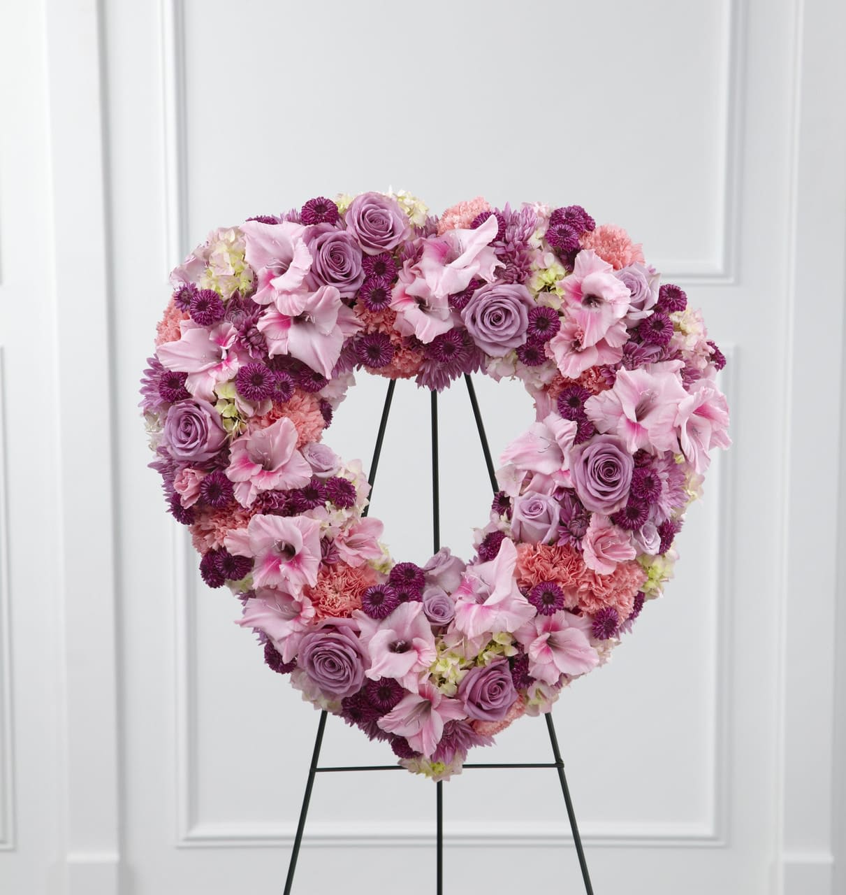 TLSP The Eternal Rest Standing Heart - The Eternal Rest Standing Heart bursts with love and sweet comfort to honor the deceased at their final farewell service. Lavender roses, pink carnations, purple button poms, lavender chrysanthemums, pink gladiolus and pink hydrangea are beautifully arranged in the shape of a heart and displayed on a wire easel to create a stunning display of warm affection that will last in the hearts of friends and family for years to come. Approximately 22-inches in diameter.  Your purchase includes a complimentary personalized gift message.