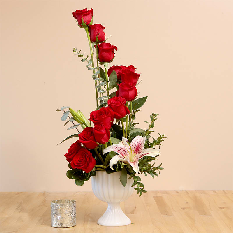 Starry Stairway Starry Stairway - Expect excited exclamations with this unusual "stairway" of vibrant roses! A magnificent 'Stargazer' lily provides a punch of pizazz and a sweet fragrance your recipient is sure to enjoy. Artfully arranged in a milk glass compote container with unusual greenery, this is sure to catch everyone's attention! One dozen red roses, seasonal greenery, and a lily arranged in a spiral in a compote style container. *Container Subject to change* Arrangement is approximately 24"H x 12"W.