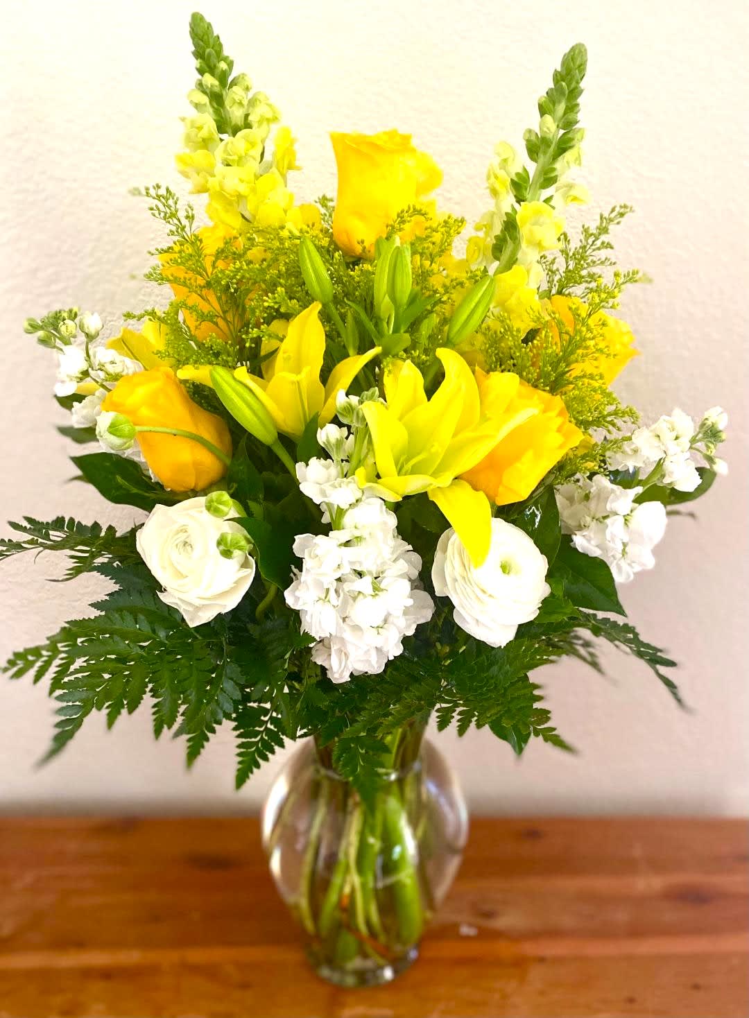 A little bit of Sunshine A little bit of Sunshine - Tall decorative glass vase arrangement composed of Snapdragons, Lilies, Roses, Lisianthus, & Stock. Various greens used. Design measures approx. 18"W x 27"H. This design can be made in various colors. Standard design pictured.