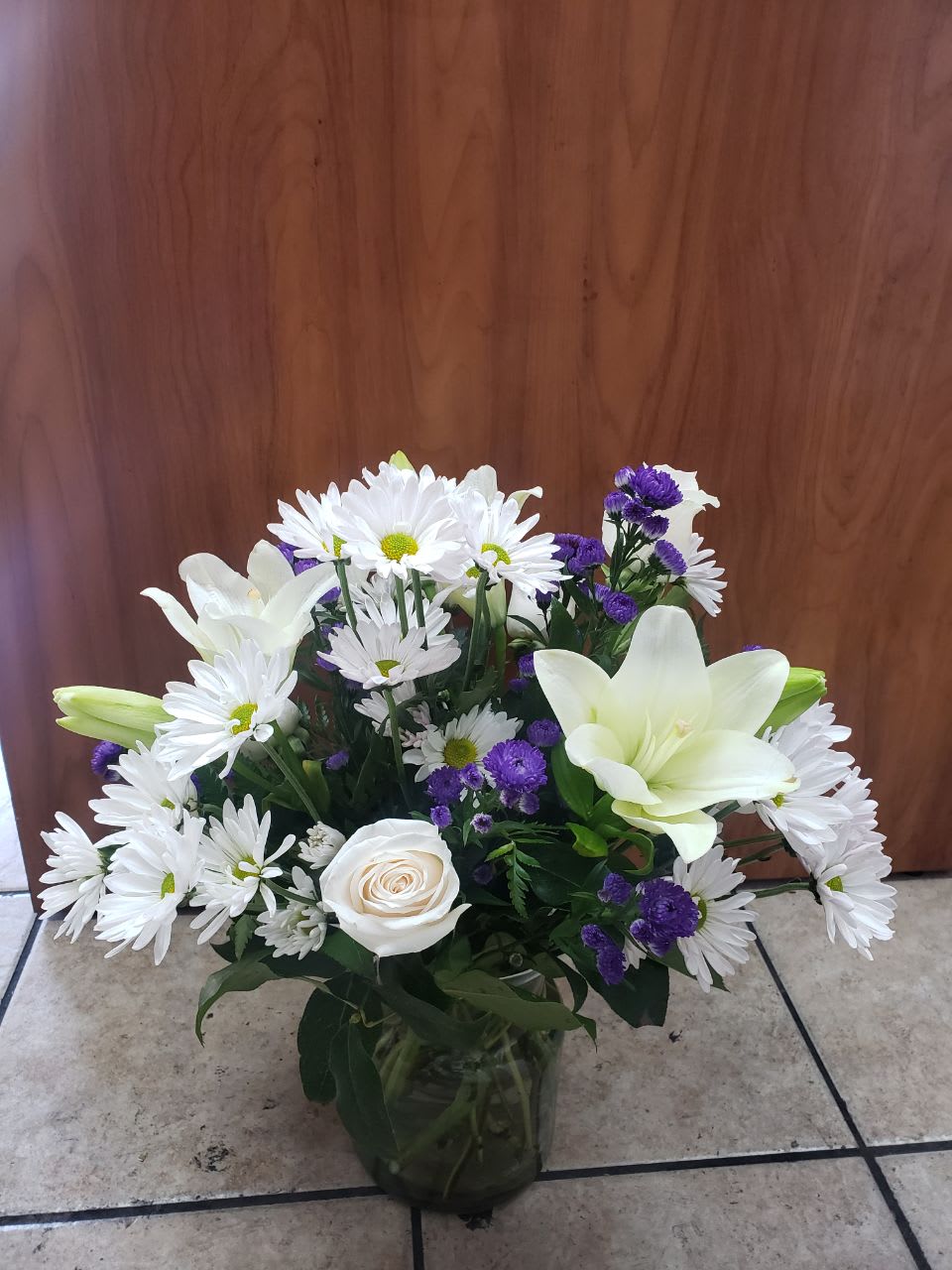 Fantastic White  - An  exquisite floral arrangement made with the most common and beautiful flowers. consists of: 5 white stems of daisies, 3  white  Asiatic lilies,4white roses  and 2 stems  of purple stares.  This beautiful flowers comes in a small  cinch vase 