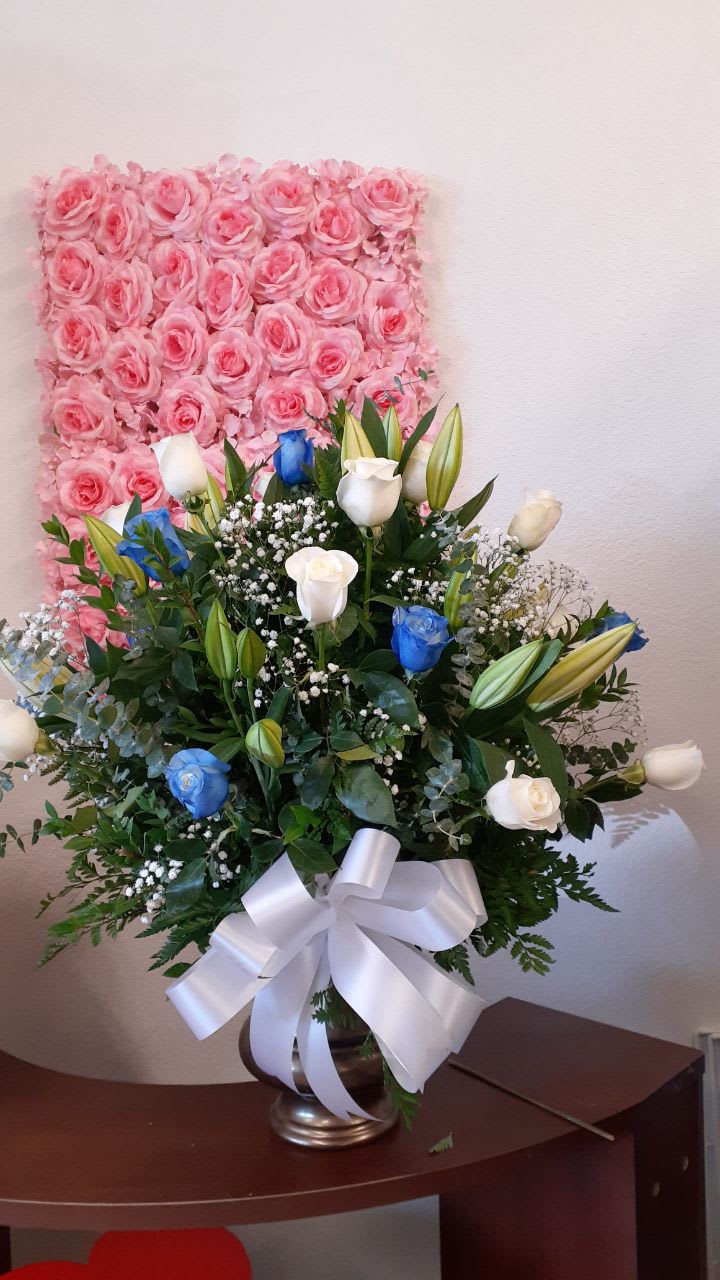 pretty in blue and white pretty in blue and white - 12 white roses, 12 royal blue roses, 4 white lilies stems 5 white stems of baby breath, with a eucalyptus stems with green like salad tips and leather leaf. These fabulous flowers come in a white plastic container with a white bow.