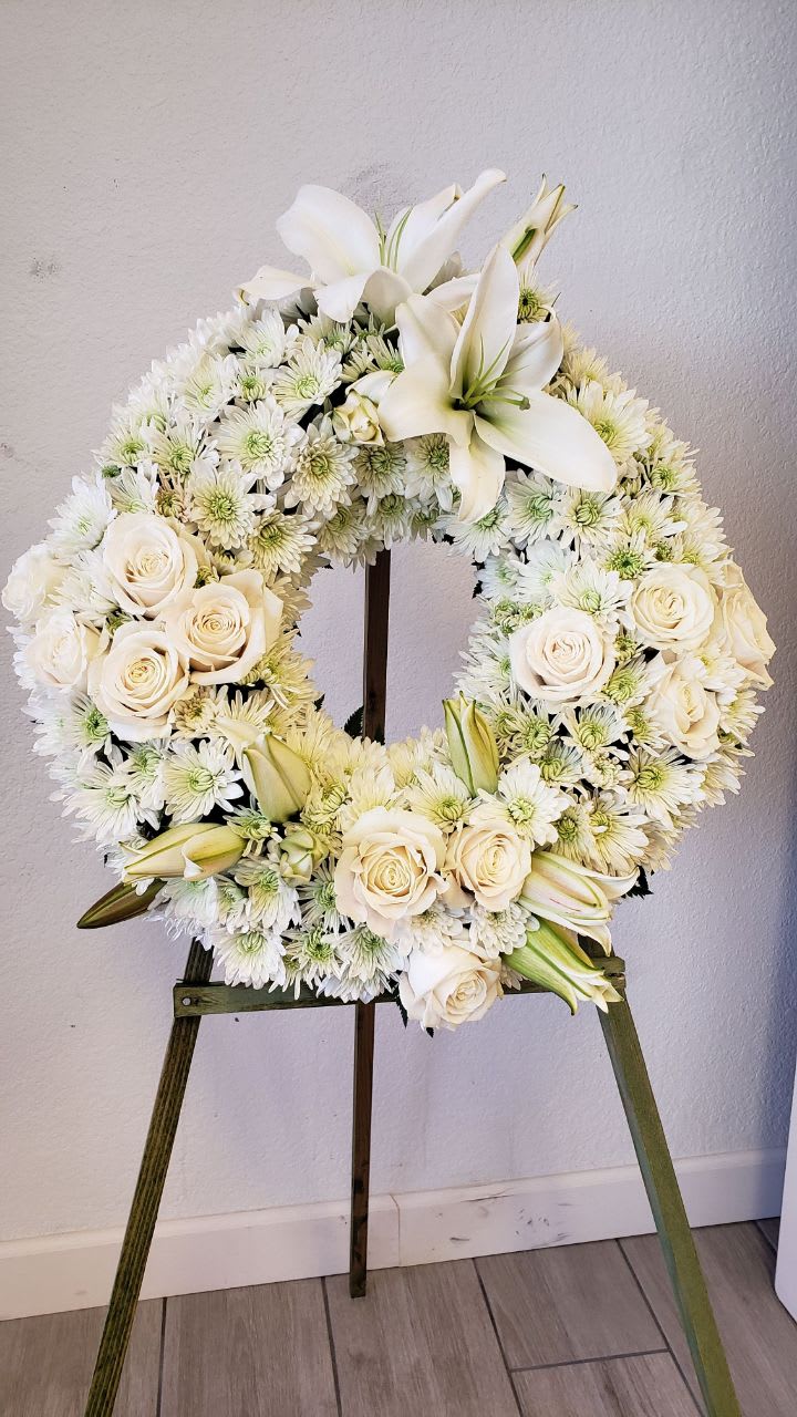 White Funeral Wreath White Funeral Wreath - 12 white roses, 2 stems of white lilies, 8 white cushion with a wood easel. size approx.. 18 inch.