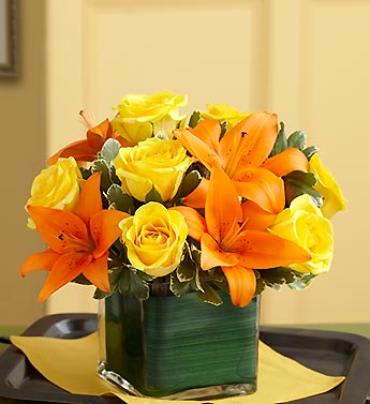 Fall Rose and Lily Bouquet Fall Rose and Lily Bouquet - A classic beauty. Bright yellow roses and vibrant orange lilies share the spotlight in this hand-designed, compact arrangement. Gathered fresh in a modern cube vase lined with exotic ti leaf ribbon to bring showy elegance to birthdays, anniversaries and any celebration.