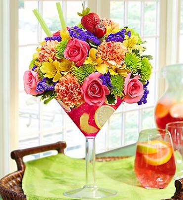 Sangria -   Spice things up with our fresh floral version of the popular wine punch. Our florists gather a kaleidoscope of roses, carnations, alstroemeria, poms and statice and hand-arrange them with slices of realistic fruit picks in a chic acrylic martini glass. Send one today and you'll have them dancing the samba in no time.   Item # 91856 