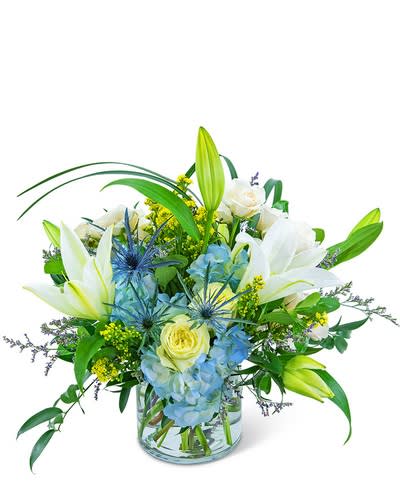 Luna Blue - The soft blues and whites of this arrangement will add a touch of tranquility to any room.  This peaceful bouquet combines blue hydrangea, white lilies, blue eryngium, white roses, lily grass, solidago, limonium and ruscus in a clear vase,
