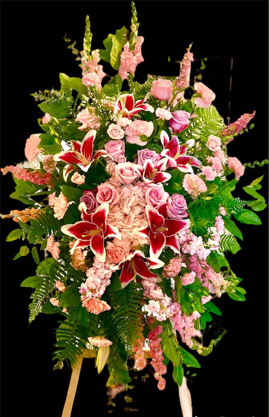 Delicate Tribute Sympathy Spray Delicate Tribute Sympathy Spray - This elegant design includes various lush blooms in various shades of Pink and Blush. It includes Roses, Hydrangeas, Stargazer Lilies, Stock, Snapdragon, and Carnations. Arranged in a starburst design and set in various foliage. This design measures approx. 29"W x 53"H and can be created in various colors upon request.