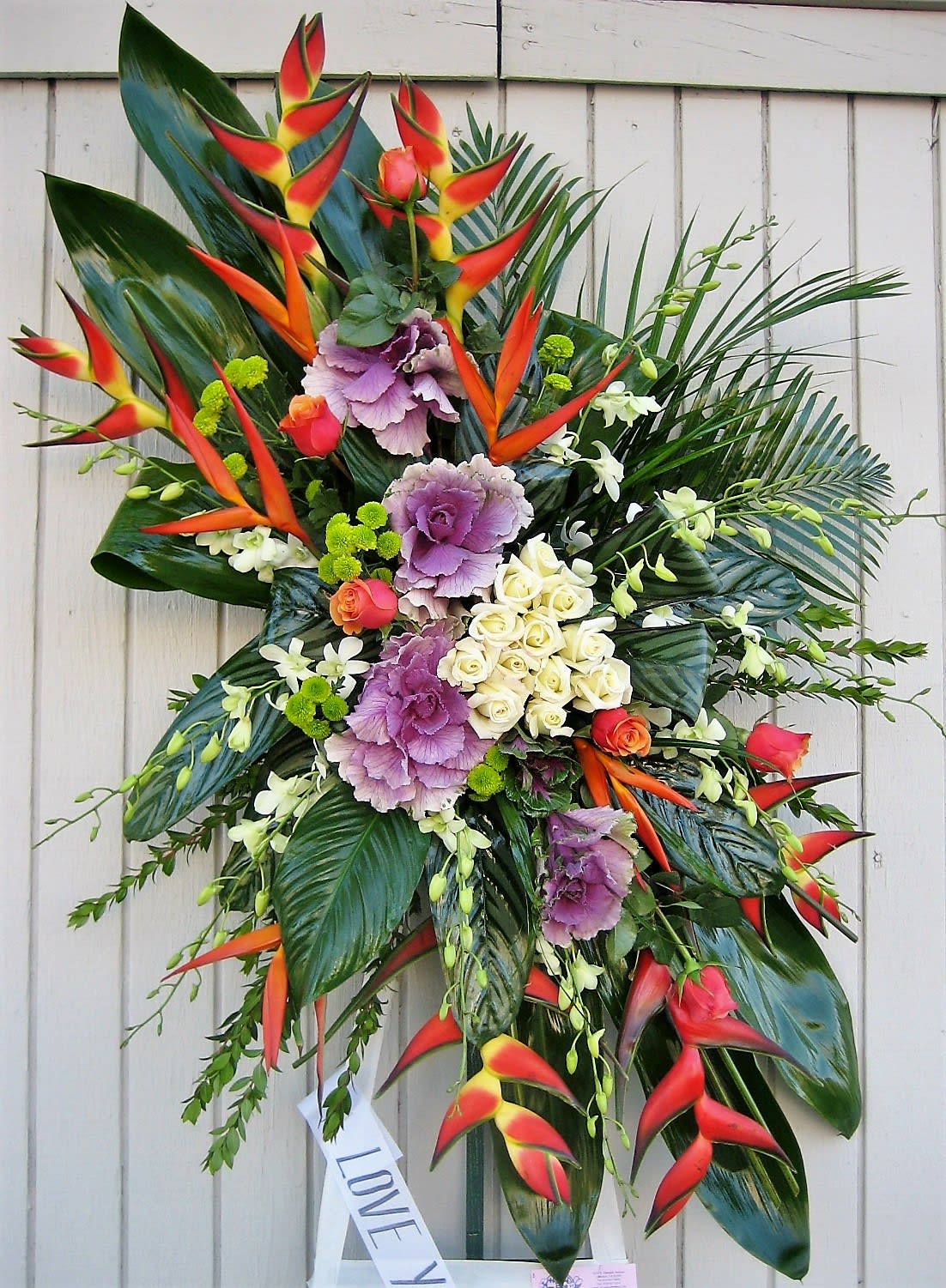 Paradise Spray - An assortment of premium cut blooms including, cabbage, birds of paradise, roses, orchids and other mixed greenery. This standing spray comes on a 6ft easel. Colors may be customized, please let us know in the section for special instructions