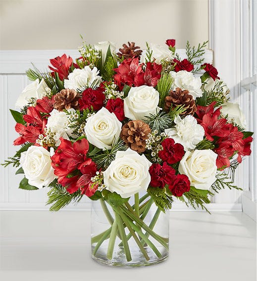 Spirit of the Season™ Arrangement Spirit of the Season™ Arrangement - If they love getting into the spirit of the season, our joyful arrangement is the best kind of surprise. This unique, asymmetrical design brings together rich red and creamy white blooms with fragrant evergreens and pinecones. Designed in a classic glass cylinder vase, it’s a gift that captures the warmth of the holidays in every last detail. All-around arrangement with white roses and carnations; red Peruvian lilies (alstroemeria); burgundy mini carnations; accented with assorted Christmas greenery and pinecones Artistically designed in a clear glass cylinder vase Large arrangement measures approximately 14.5"H x 12.5"W Medium arrangement measures approximately 14"H x 12"W Small arrangement measures approximately 13"H x 11"W Our florists hand-design each arrangement, so colors, varieties and container may vary due to local availability To ensure lasting beauty, Peruvian lilies may arrive in bud form and will fully bloom over the next few days