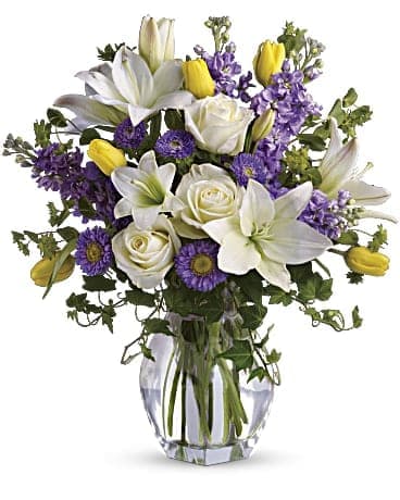 The Spring Waltz Bouquet - Dance into spring! Send this feminine bouquet of favorite spring flowers to brighten someone's home with the playful beauty of nature. Such a pretty way to say, &quot;I'm thinking of you!&quot;  This white, lavender and yellow bouquet includes white asiatic lilies, cream roses, yellow tulips, lavender stock, lavender matsumoto asters and greens including bupleurum, ivy and seeded eucalyptus. Delivered in a gorgeous reception vase.  SUBSTITUTION POLICY – Always deliver the freshest flowers! Please note the bouquet pictured reflects our original design.  If the exact flowers or container in this arrangement are not available, we will create a beautiful bouquet with the freshest available flowers.