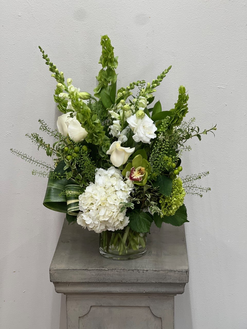 Imposing Greens Bouquet - This majestic bouquet is in a short cylinder vase but the greens sure take it to a new height. Elegant and clean, this bouquet is sure to wow them all.   Flowers and colors may vary depending on availability. 
