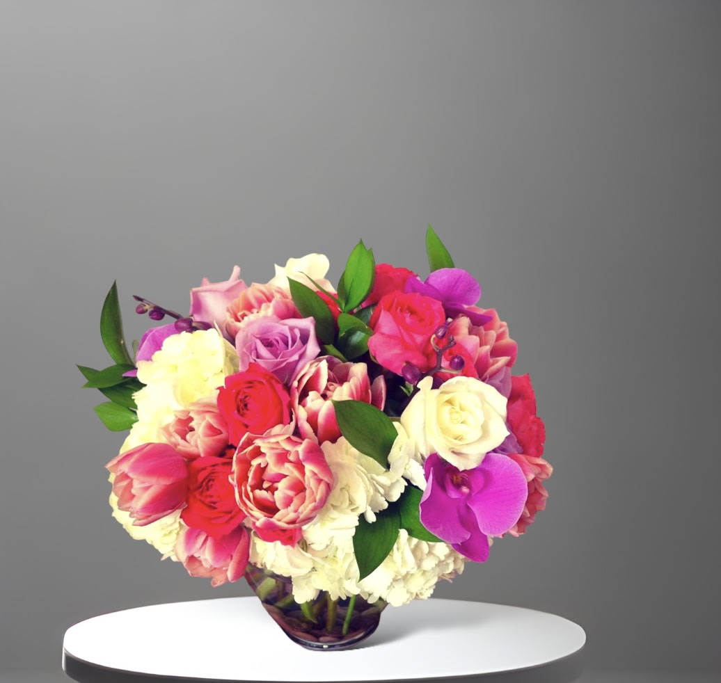 Bright Tulip - A bright colorful mix of Spring flowers. Tulips, roses, hydrangea and orchids with seasonal foliage arranged in a glass vase.