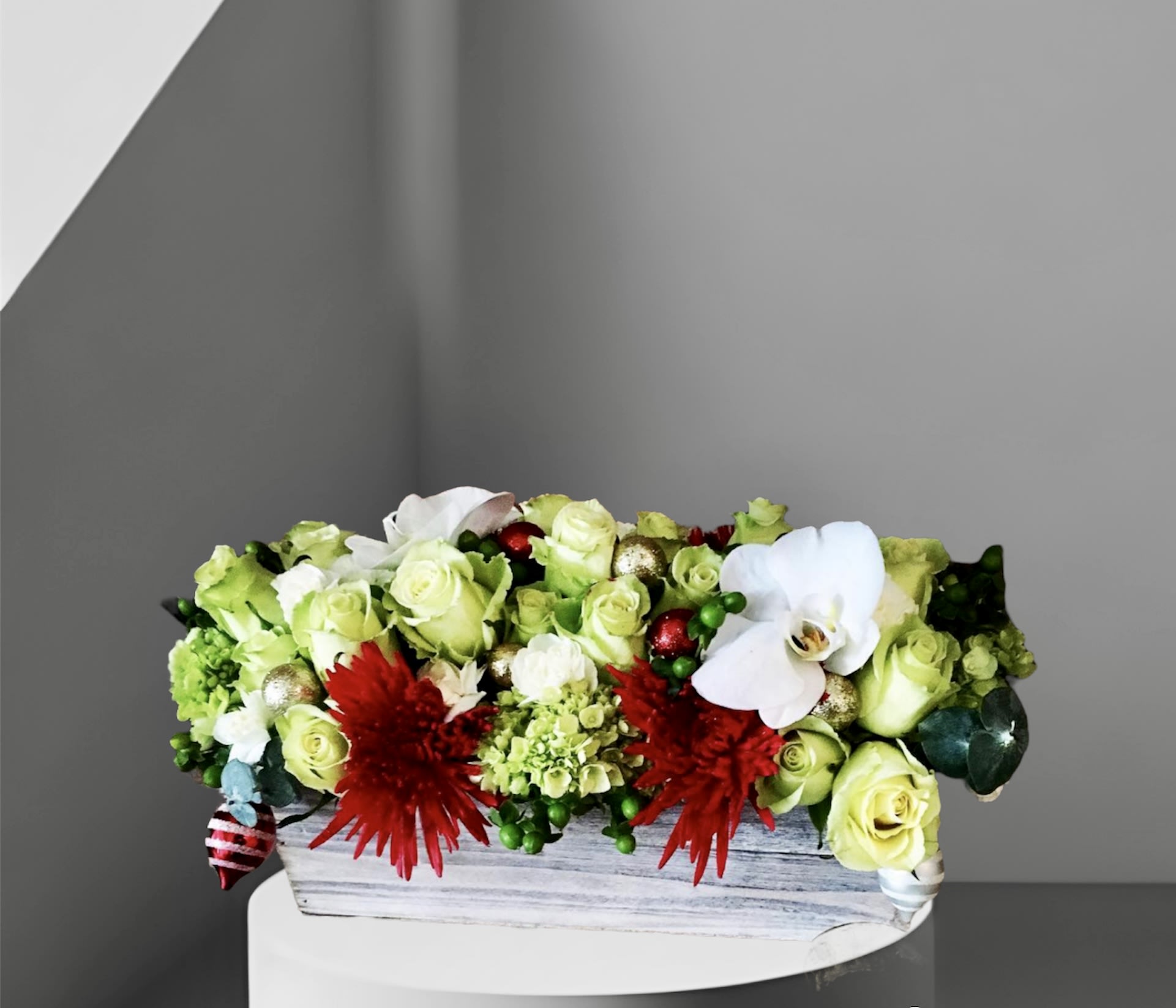Holiday Centerpiece - A festive addition to your holiday table. An arrangement of holiday colored roses, hydrangea, hypericum berries, orchids, and mums in a birch wood box accented with sparkling ornaments.