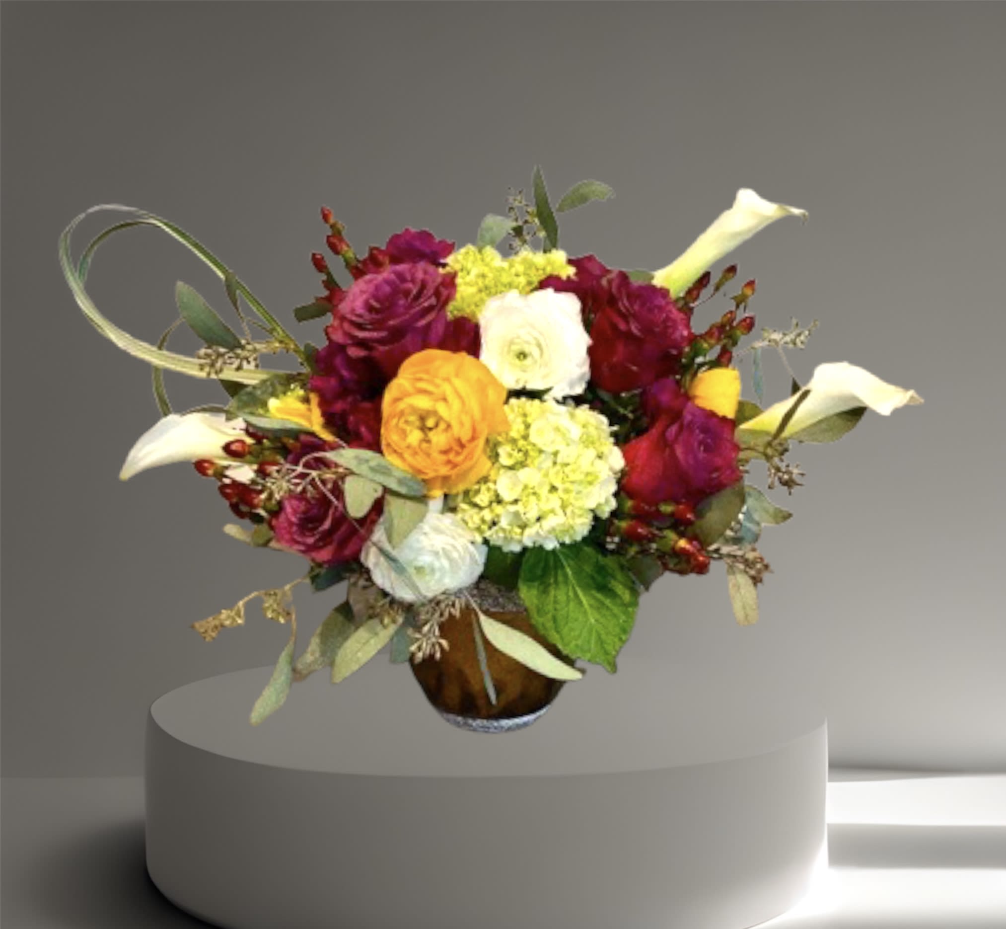 Fall Beauty - A lovely mix of roses, calla lilies, hydrangea, hypericum berries, and seasonal flowers and foliage in a low ceramic vase. 