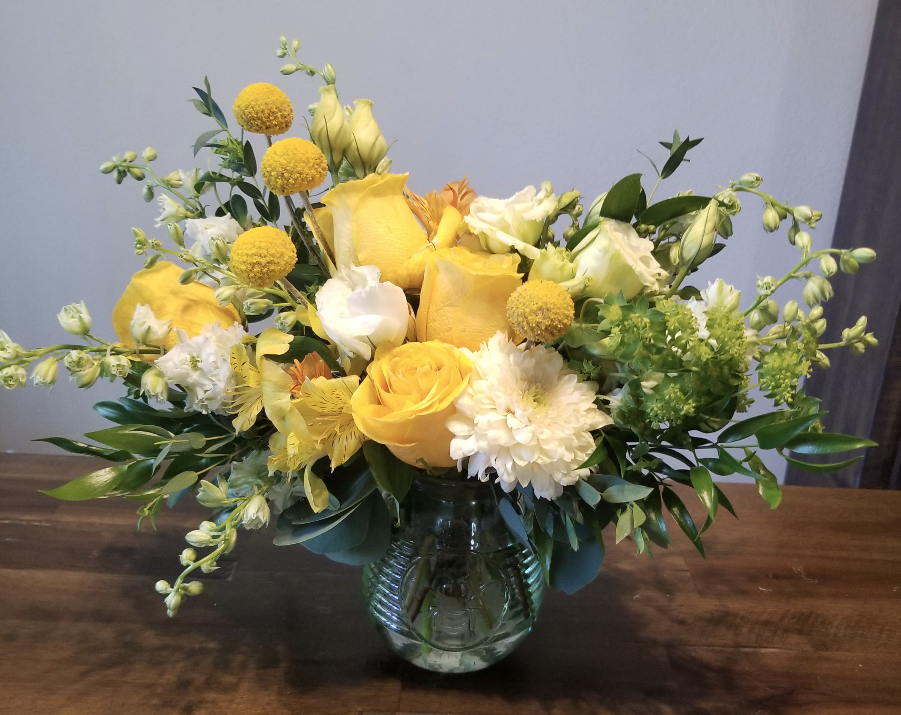 Little Darling Happy - A bright cheerful darling little arrangement of yellow and white flowers such as roses, stock, lisianthus, daisies, larkspur etc…