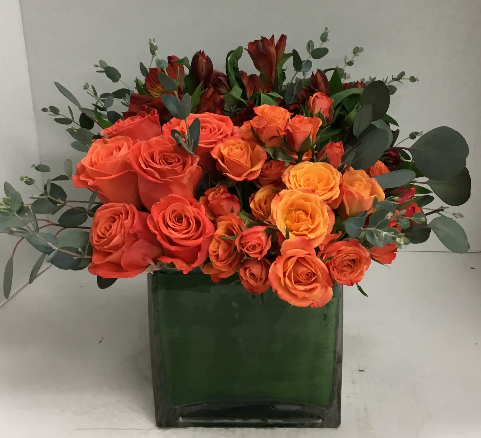 Orange Bang! - Delightful arrangement of orange Roses, spray roses, alstromeria and eucalyptus in a leaf-lined vase