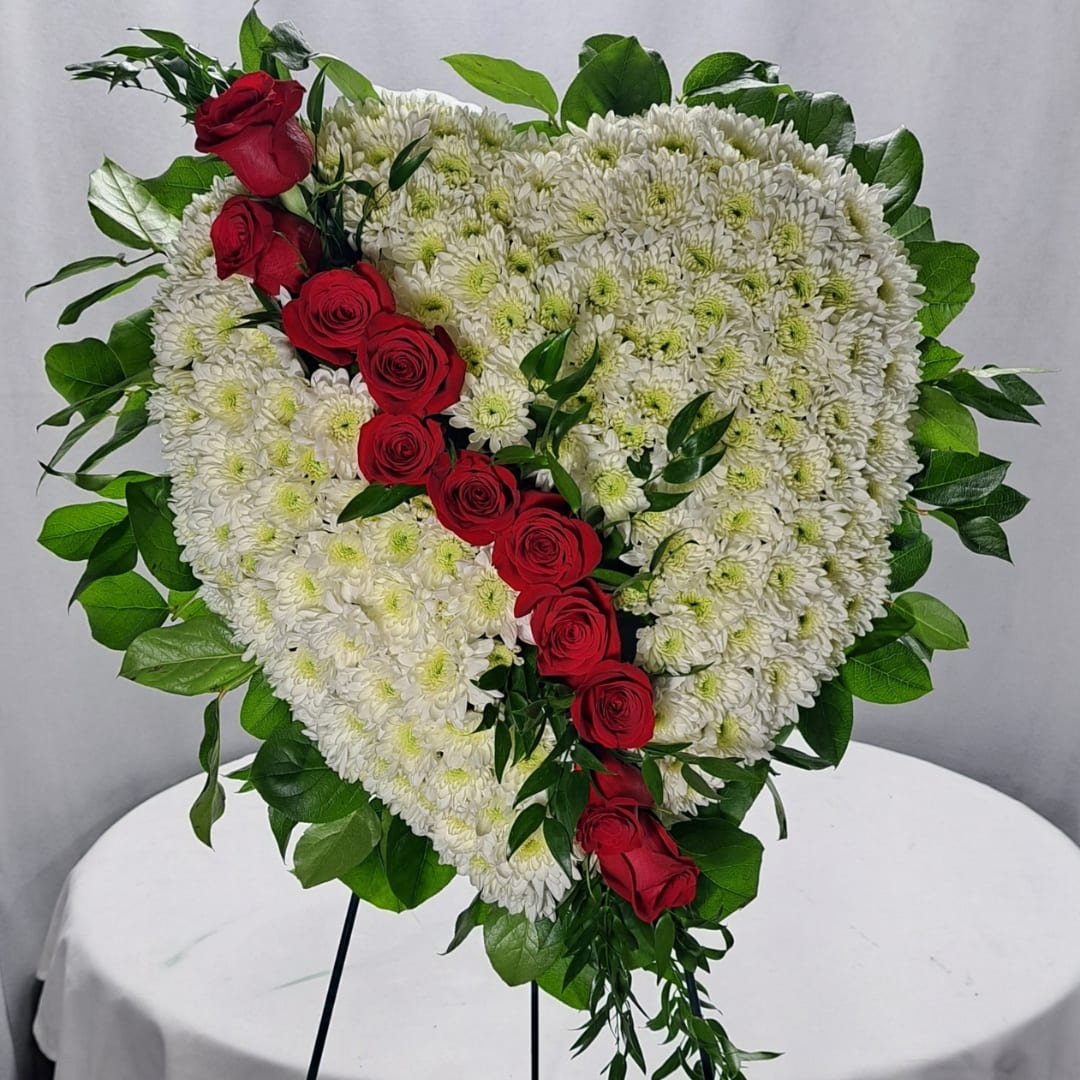 Lined Heart Standing Spray - At ABM Floral Studio, we know that it can be difficult to find the right sentiment to express your deepest condolences. Our Lined Heart Standing Spray is one thoughtful way to convey your sympathy and show your love to those mourning. A beautiful 22&quot; in diameter heart-shaped spray is the perfect way to pay tribute to the departed. The Lined Heart Standing Spray features a serene combination of white chrysanthemums, red roses, ruskus, and salal leaves – a gesture of comfort that speaks louder than words. With its timeless beauty and profound meaning, the Lined Heart Standing Spray is sure to remind everyone at the funeral of fond memories shared with their loved ones. Honor their memory with an unforgettable tribute from ABM Floral Studio.