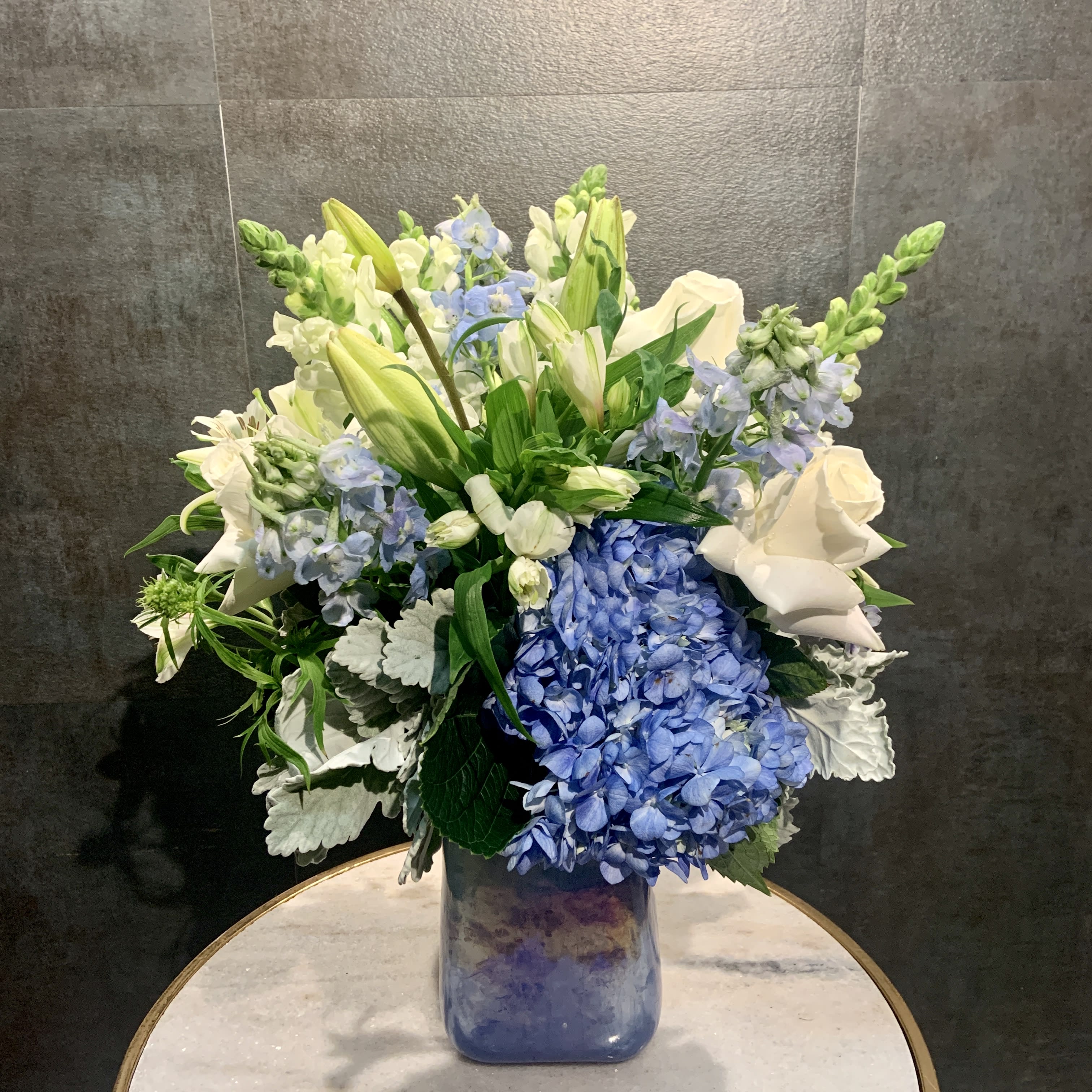 Beautiful in Blue - A stunning arrangement of blue and white flowers in a simple yet elegant vase. 