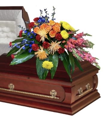 Garden Casket Spray - This garden casket spray of bright blossoms in shades of red, orange, blue and yellow, arranged against a backdrop of greenery, will celebrate a life well-lived.
