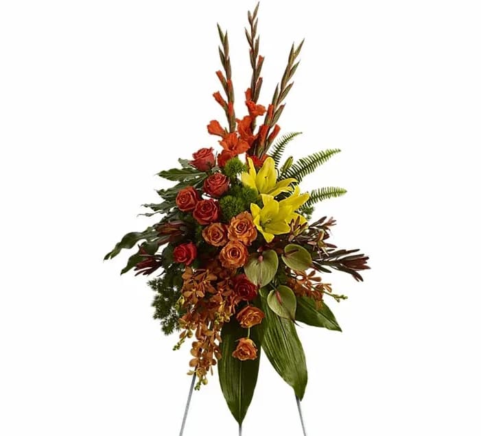 Tropical Tribute Spray - Tropical highlights balance with lush earth tones to offer hope and encourage reflection - a vivid spray that expresses deep and generous tribute. A breathtaking assortment of flowers such as yellow asiatic lilies with orange orchids and roses red gladioli and protea and yellow chrysanthemums delivered on an easel.