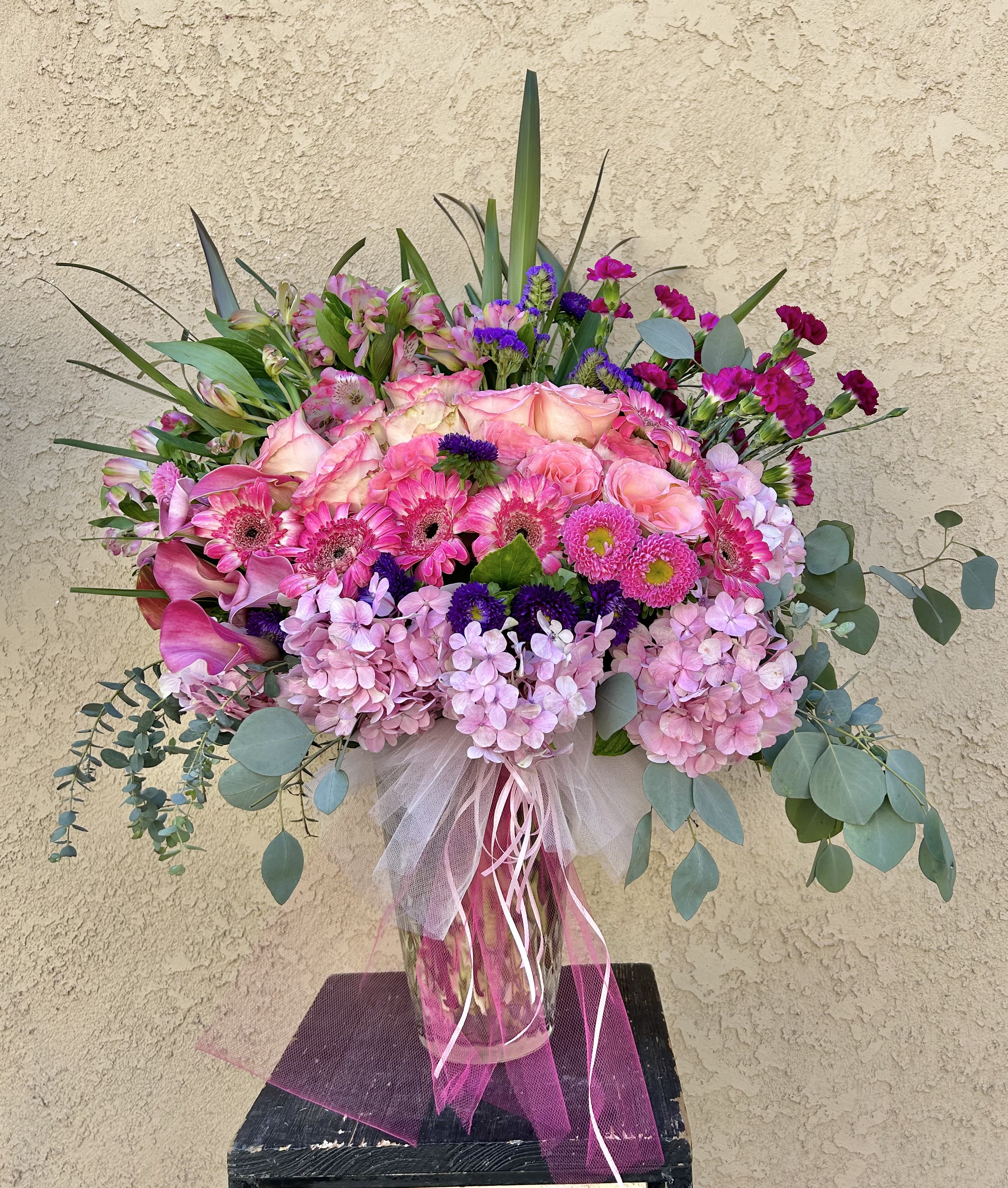 Our World - Beautiful pink and purple floral arrangement featuring roses, hydrangeas, daises, calla lilly , and seasonal accents 