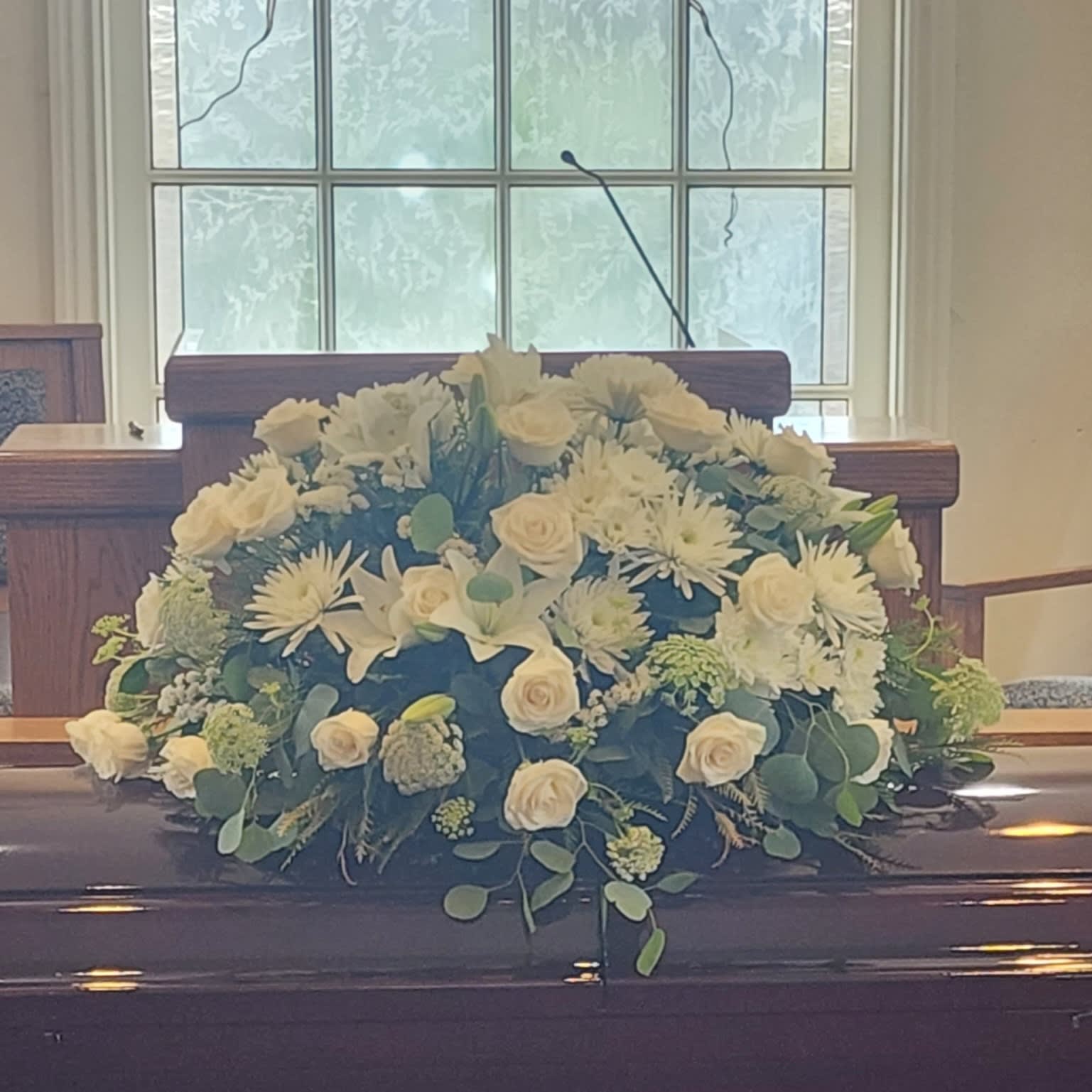 Tranquility by BloomNation™  - An all white tribute, this full casket spray is pure and tranquil. Featuring a variety of white flowers and greenery, this elegant spray evokes a feeling of peace. 