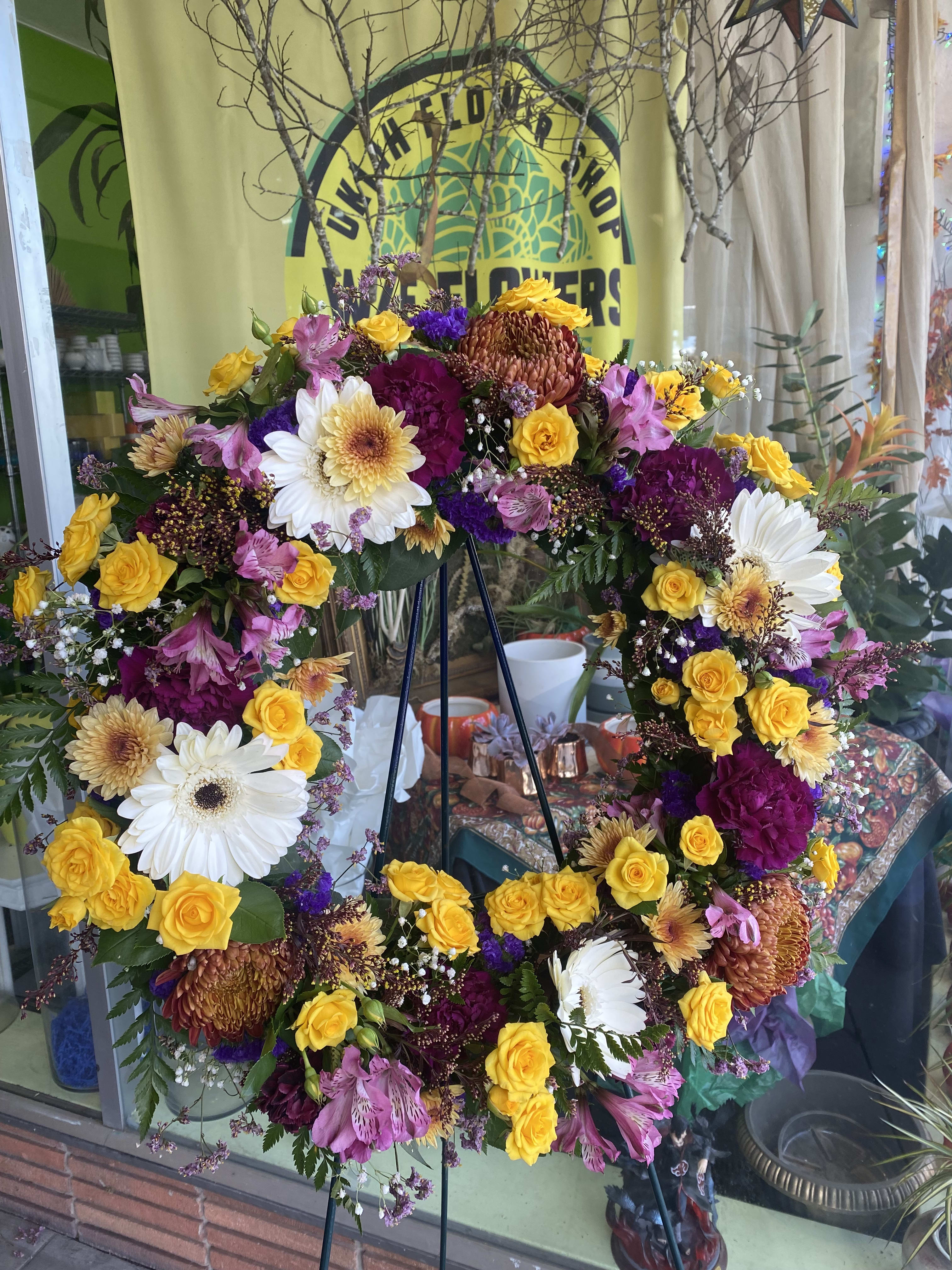 Bright Mixed Colors Memorial Wreath - A beautiful multicolored tribute wreath that celebrates a bright and full life and a peaceful passing. The wreath is accompanied by an easel.   Please let us know if there is a particular flower and/or color you would like us to use for your wreath and we will be happy to customize if the season permits.