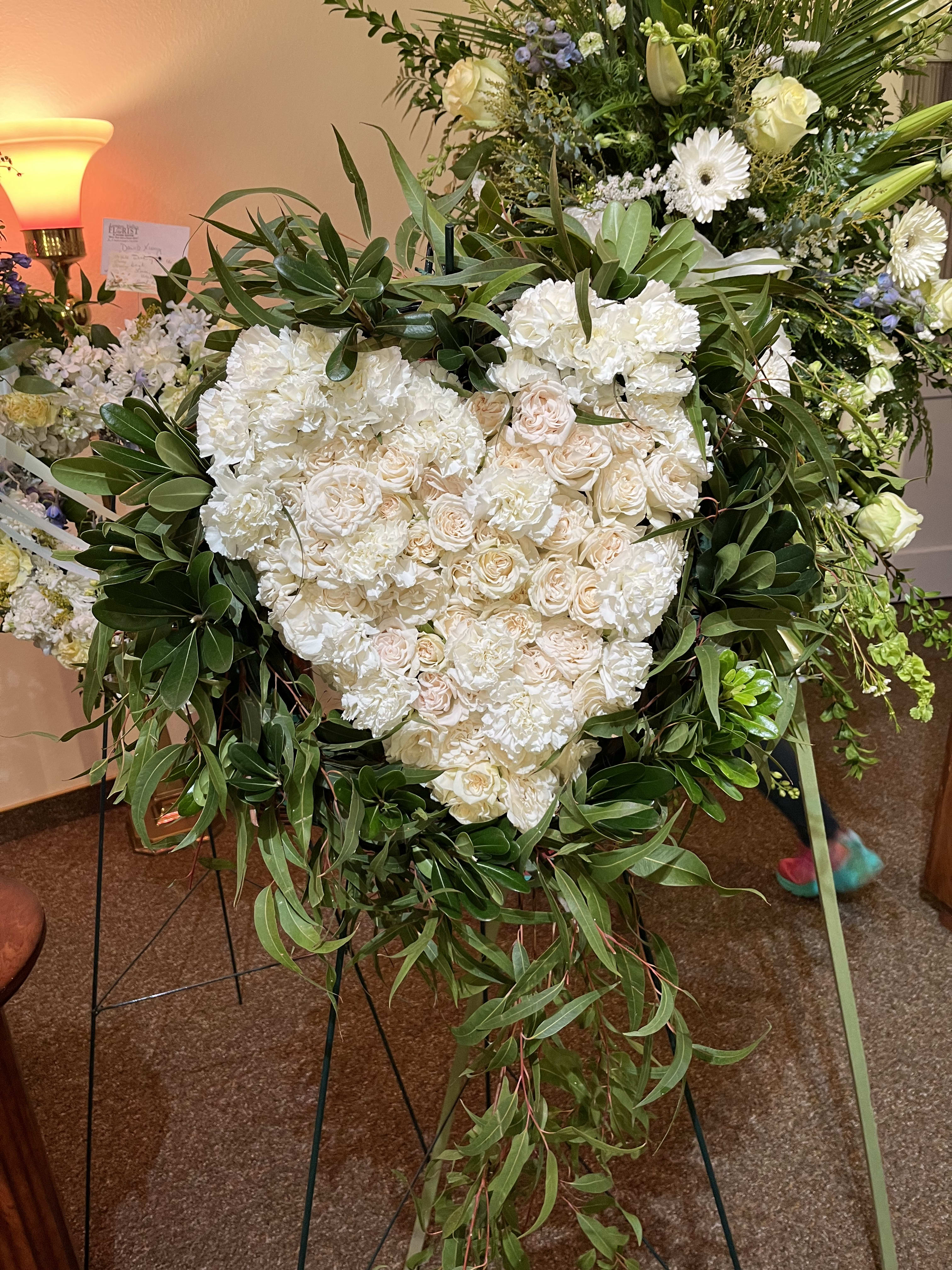 Sympathy Heart - Beautiful display of a pure white heart encased around dark contrasting green foliage. 