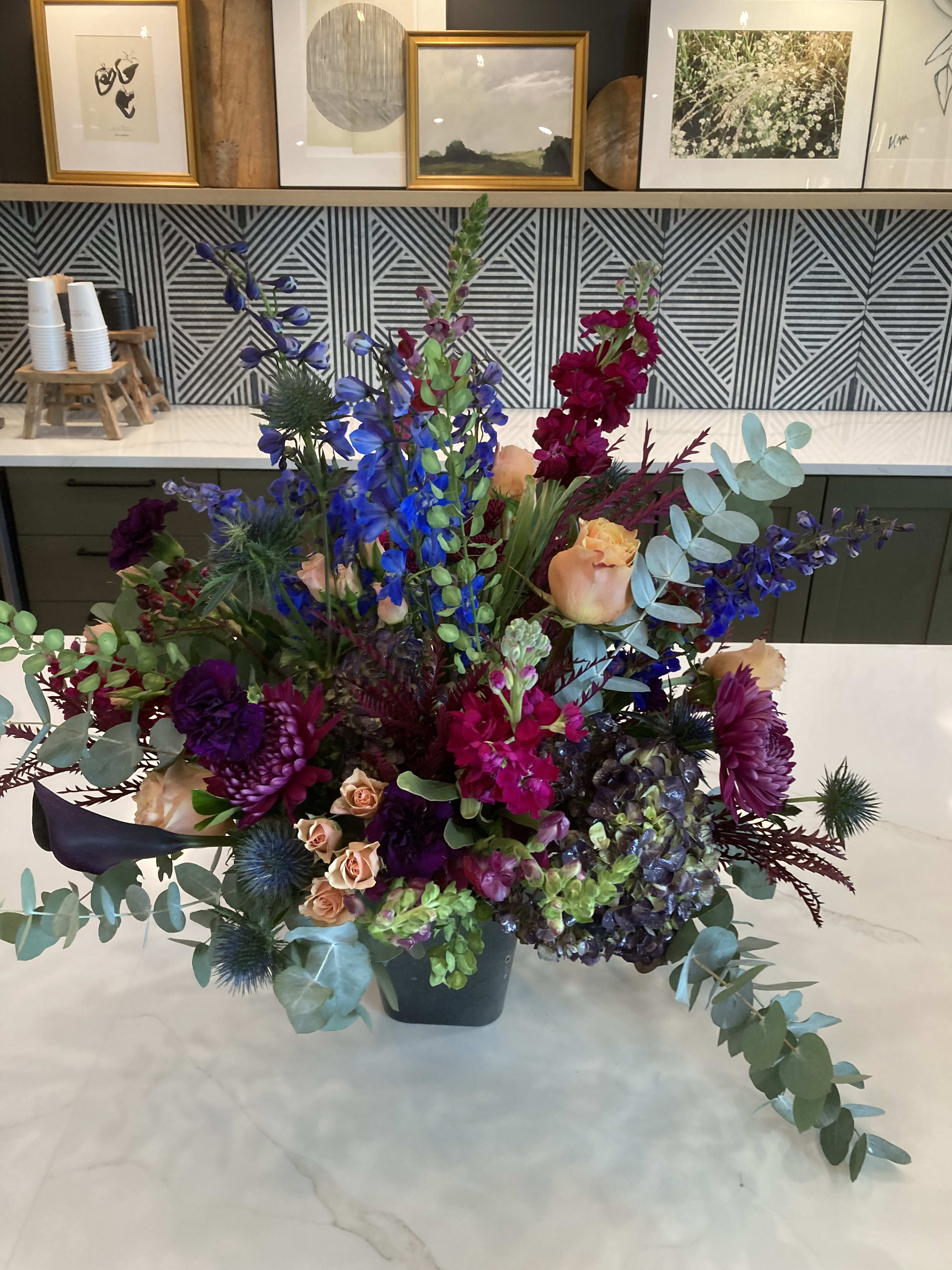 Moonlight Beams - A grand bouquet with dark moody blooms. Dark purple calla lilies, delphinium, spray roses, thistle, and stock.