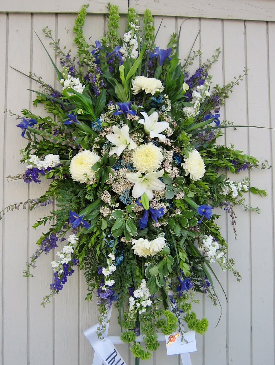 Blue Standing Spray Blue Standing Spray - Designed with fresh larksbur, blue iris, mums, bells of Ireland and other mixed wilflowers and greenery. This standing spray comes on a 6ft easel. Colors may be customized, please leave color preference in the special instructions section.