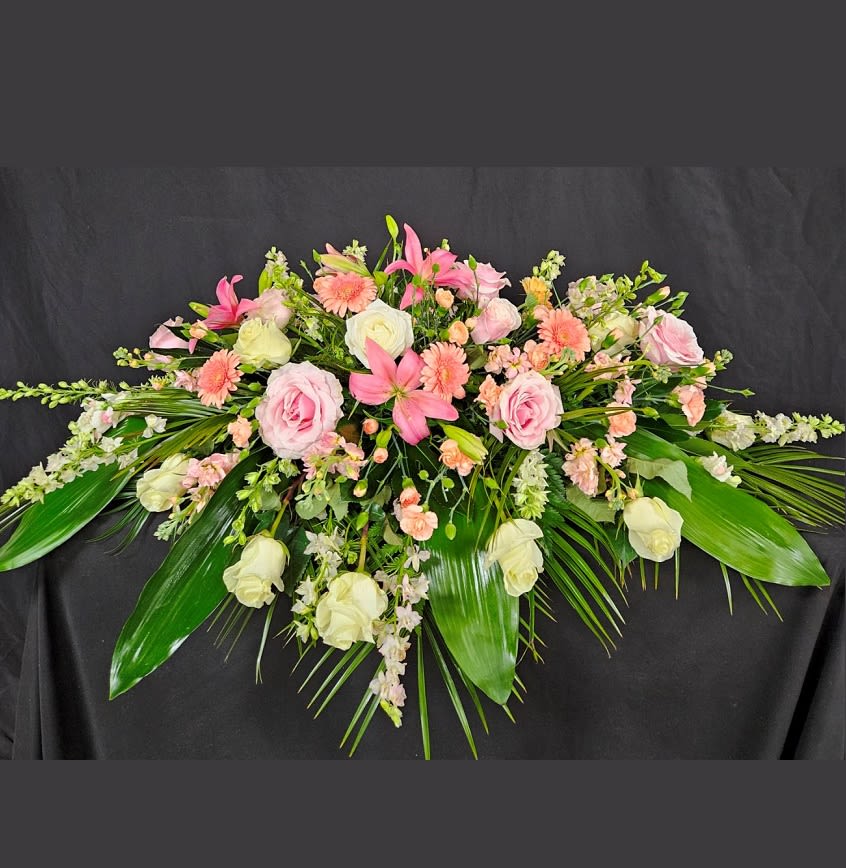 Peach Comfort Casket Spray - The soft peach colors of roses, gerbera daisies, asiatic lilies, and stock are mixed with white snapdragons, stock, and mini carnations with either pink or blue accent flowers such as larkspur, carnations, iris, and hydrangeas.
