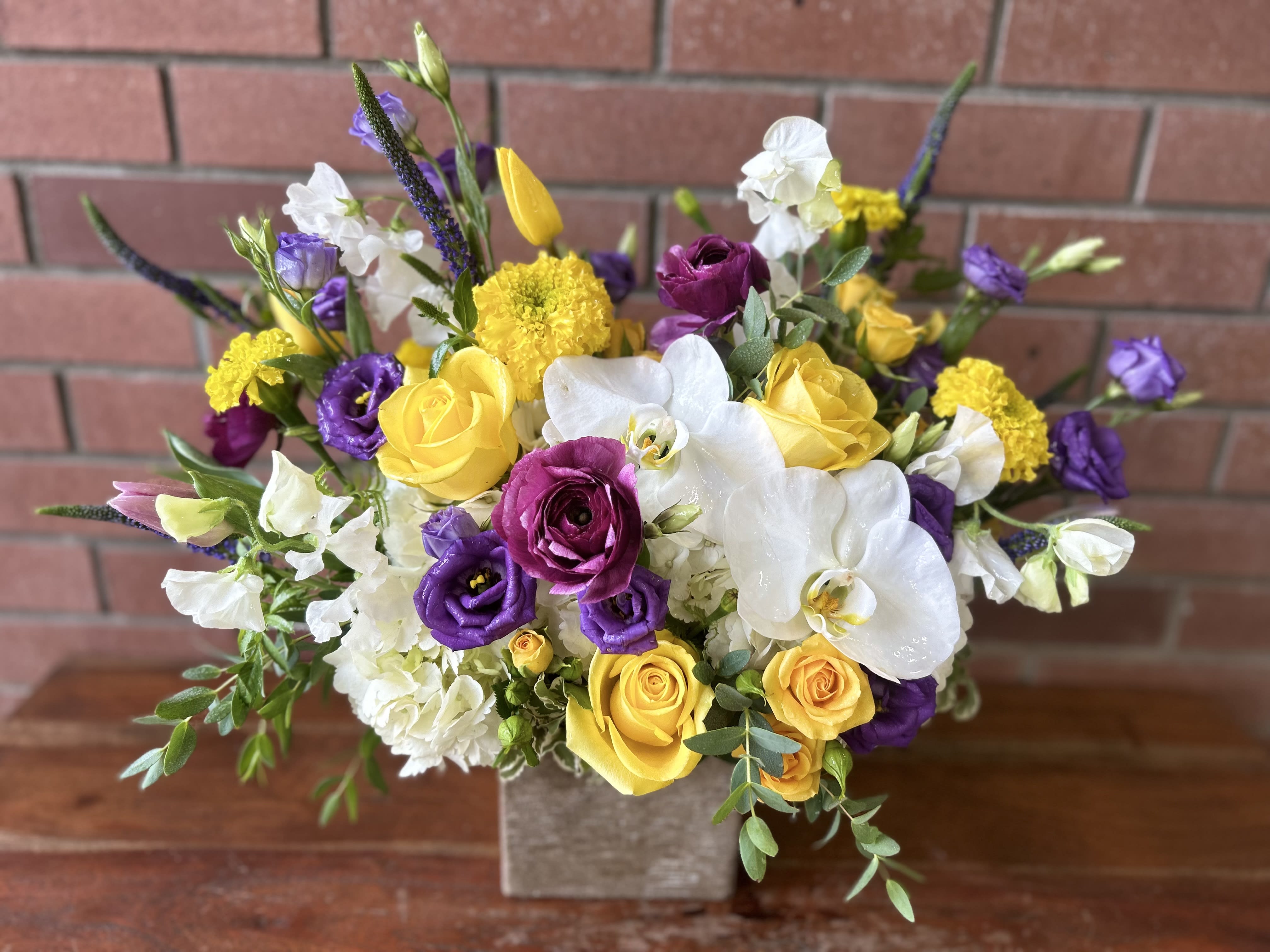 Dreamscape Garden Bouquet  - Lush seasonal flowers including sweet peas, orchids, hydrangeas, yellow roses and spray roses, lisianthus, ranunculus, tulips, marigolds, Veronica and gorgeous wispy eucalyptus accents designed in a modern gold cube vase.  