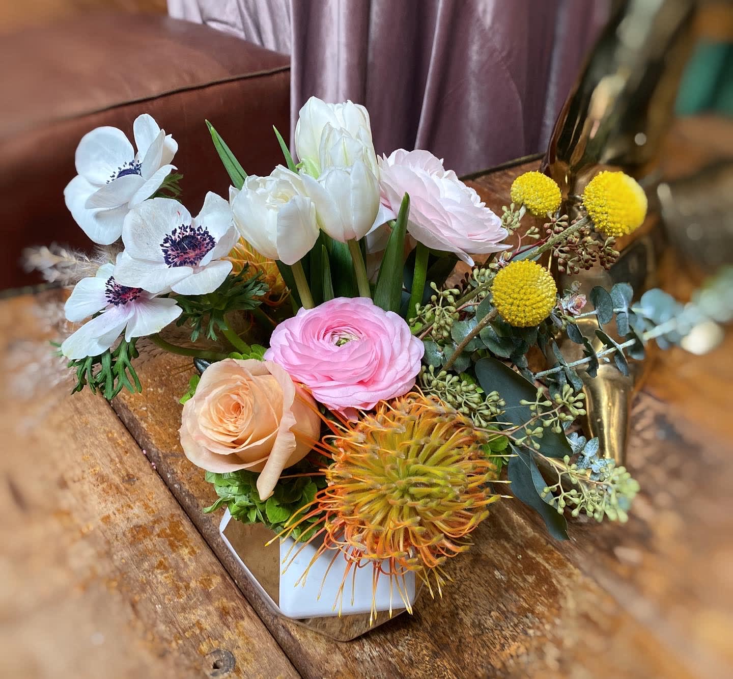 Bell - White anemone, tulips, peach roses, orange pin and  yellow billy ball. Has a variety of different colors, perfect if you need a bit of color in your life. 