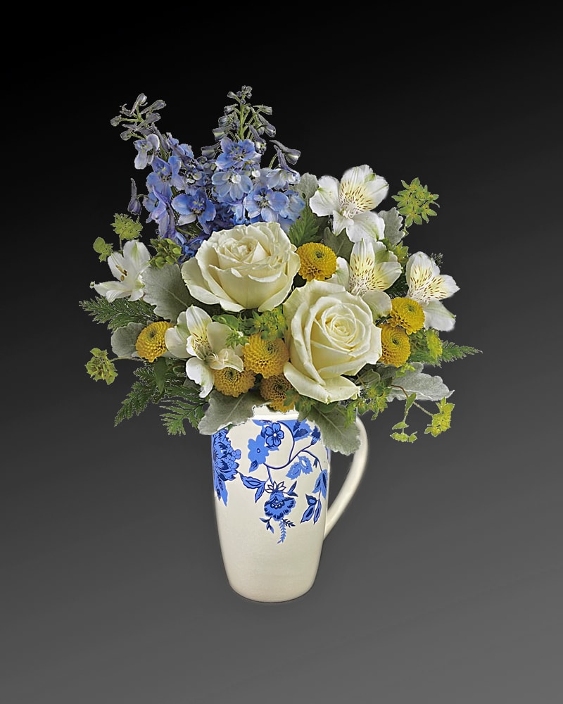 EC Welcome Little One Bouquet - Welcome the new addition with a charming EC coffee mjug bursting with a sweet bouquet of roses, mums and delphinium. White roses, white alstroemeria, yellow button spray chrysanthemums, and blue delphinium are arranged with bupleurum, dusty miller, and leatherleaf fern. Delivered in a Baby Block. Orientation: All-Around  Standard size about 9&quot; H 10 &quot; W   Premium size: about 1 foot H 13&quot; W