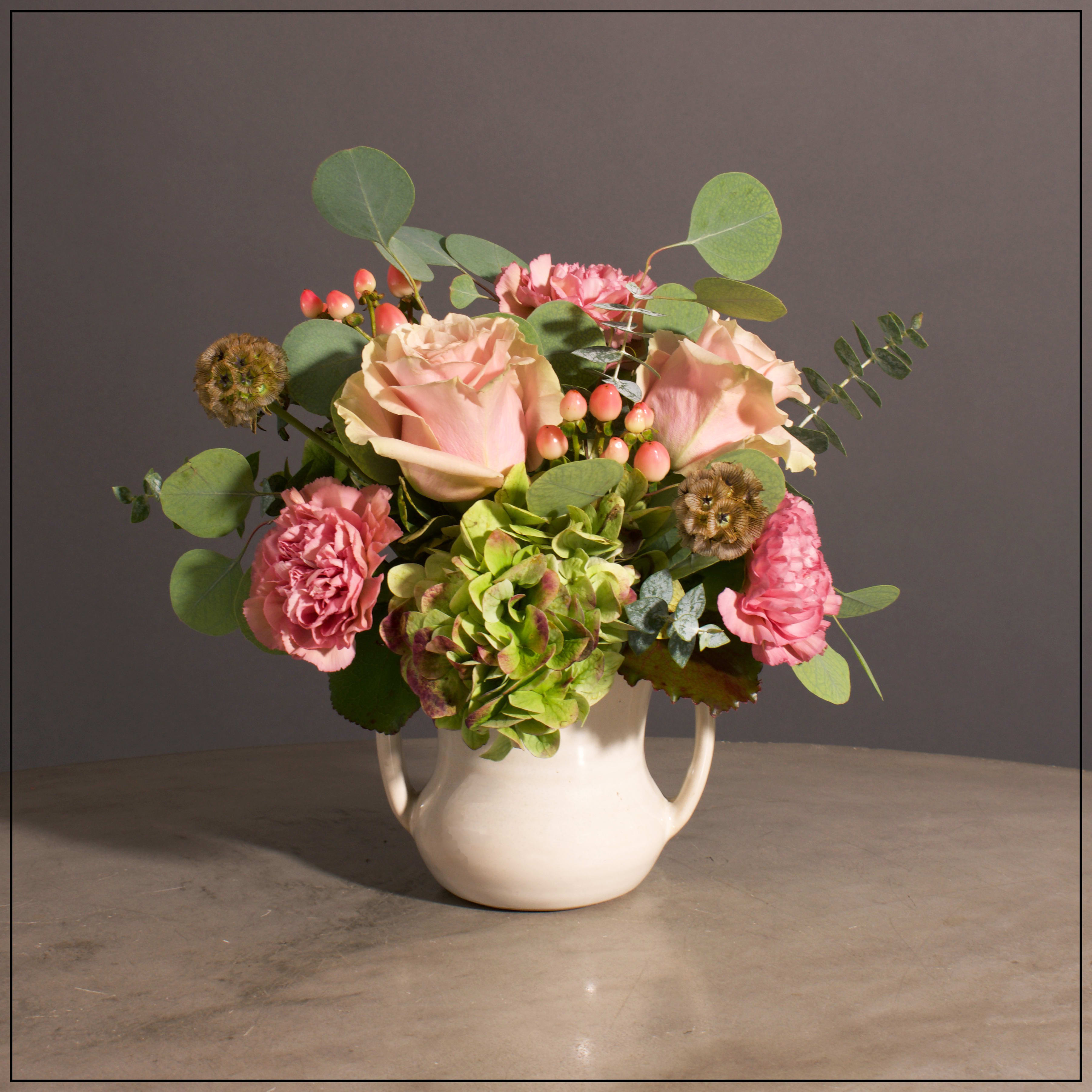 Country Urn - Roses, Hydrangea, Carnations, Hypericum and Scabiosa Pods with mixed Eucalyptus  in an Ivory Handled Ceramic Pot.   Approximately 11&quot; H x 11&quot; W