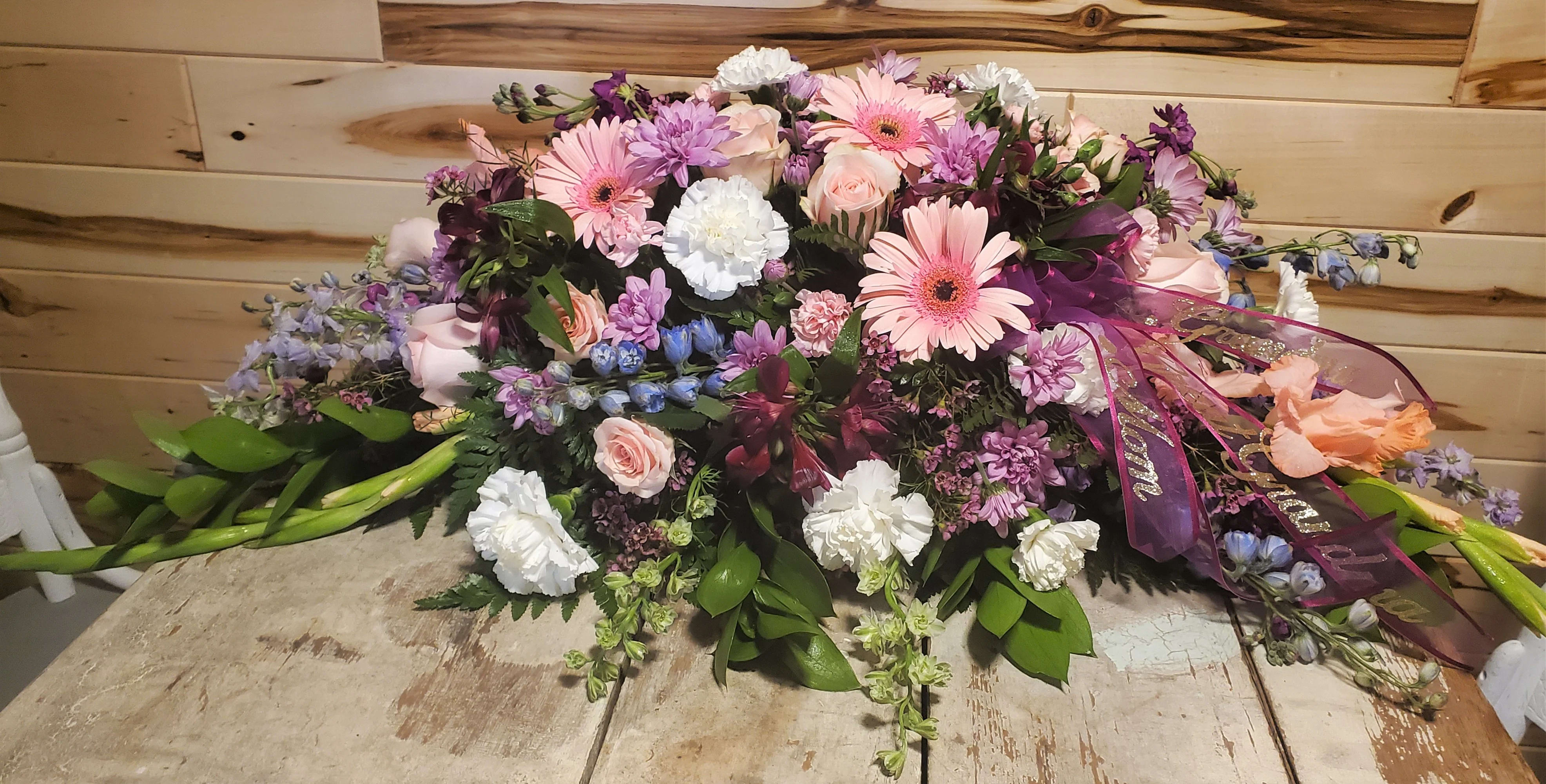 Pastel Memories - A nice soft blanket of pastel colors to lay on your loved one's casket. Gerberas, roses, carnations, delphinium, gladiolas, larkspur, cushion poms, mini carnations, stock, alstroemeria, spray roses and wax flowers.