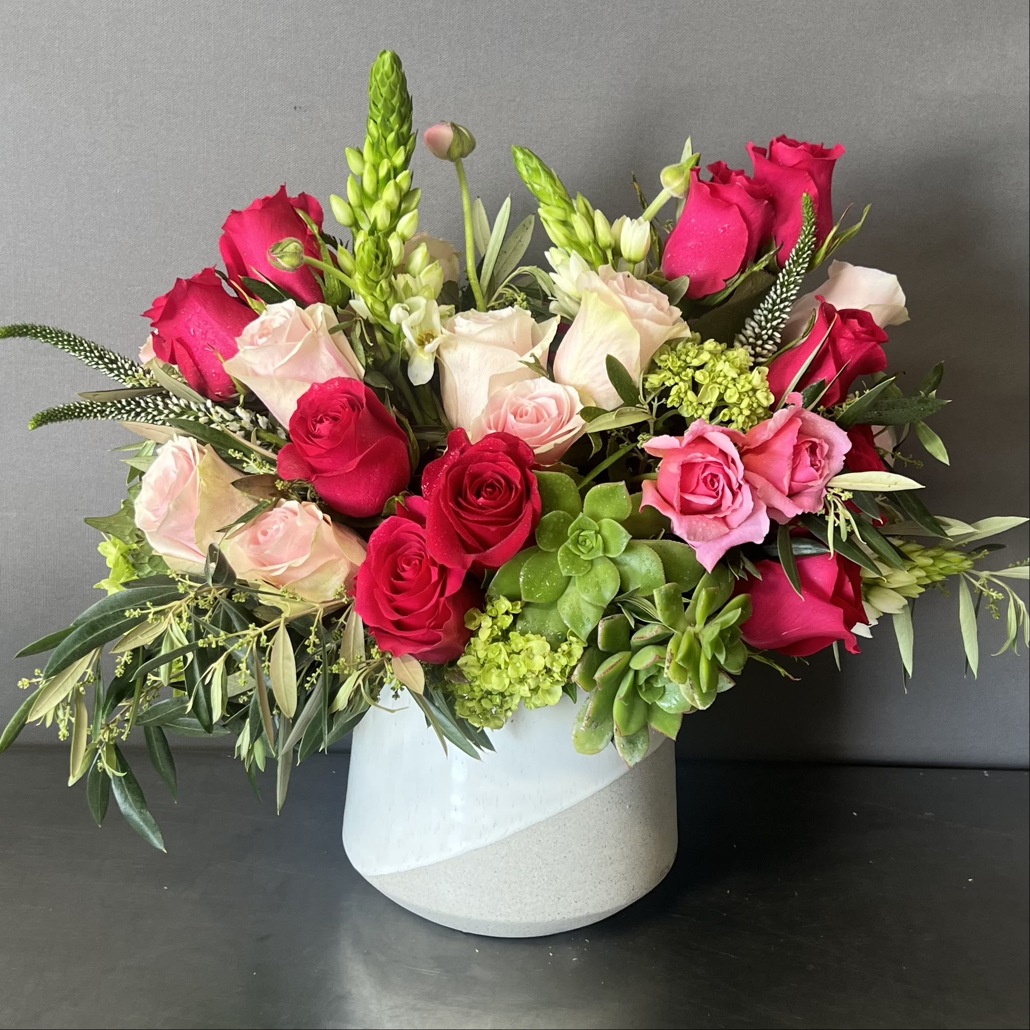 PINK DELIGHT - This beautiful floral arrangement is designed in a white and sand 6&quot; ceramic vase. This arrangement has imported Ecuadorian roses and seasonal local and imported flowers. 