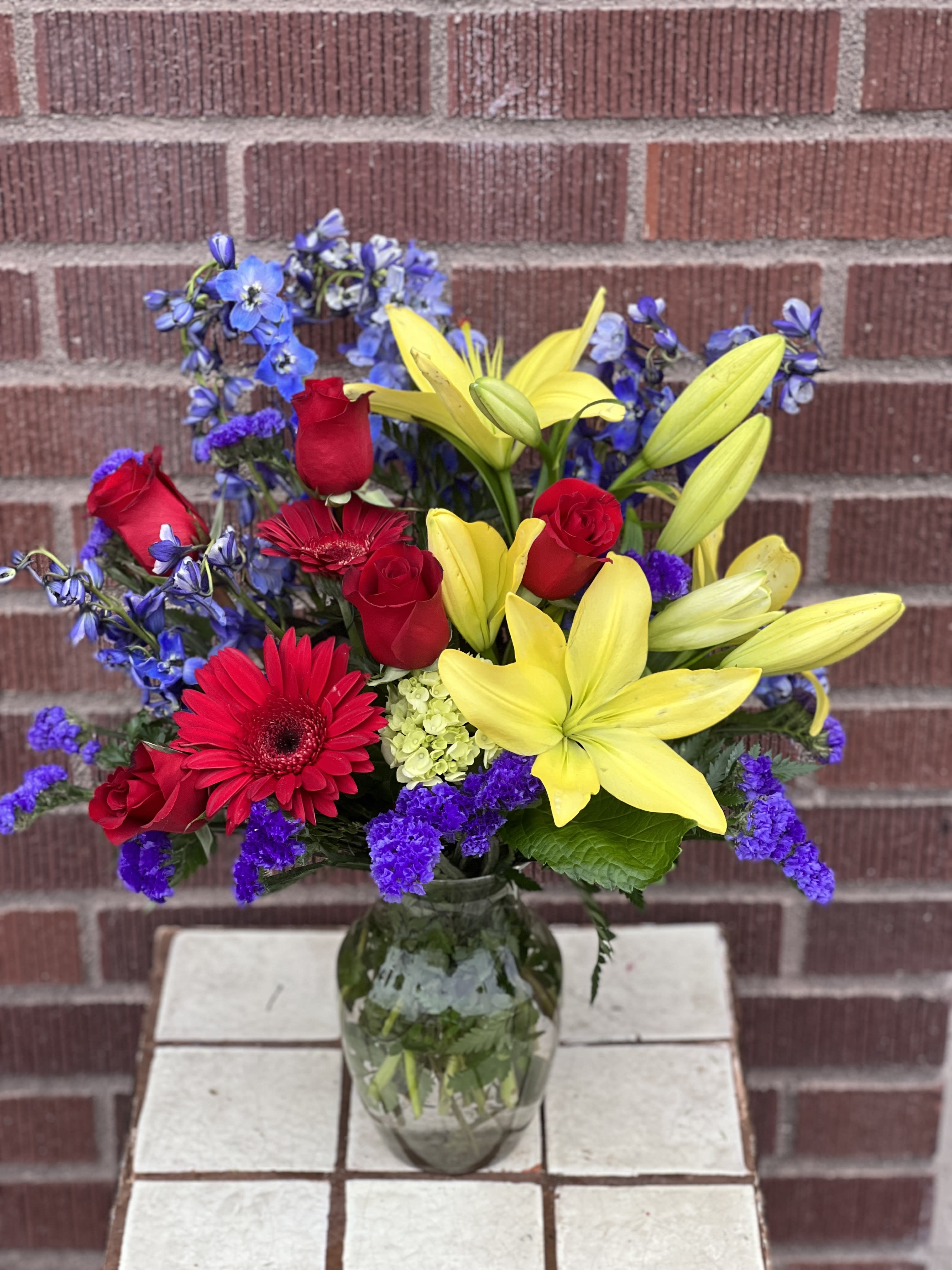 Primary Petals - In a mix of primary colors, this bright arrangement designed by one our local girls is sure to lift spirits!