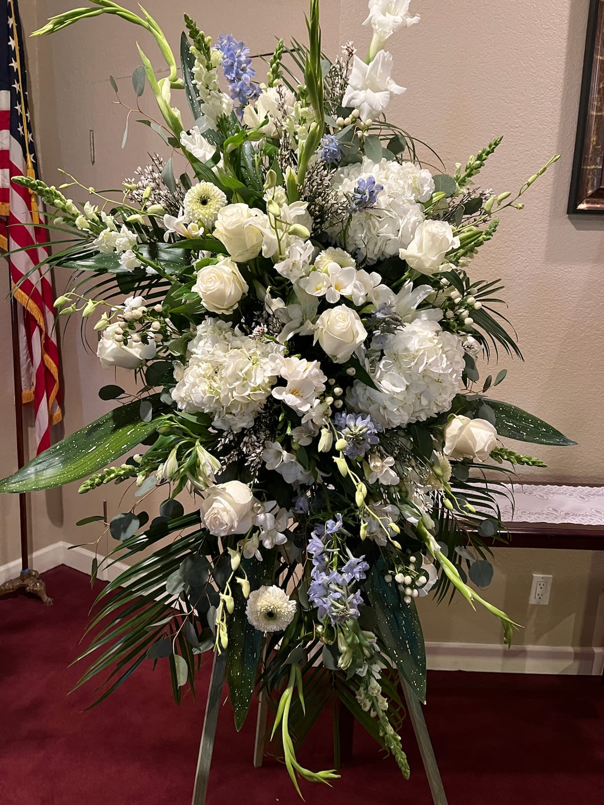Large White Standing Spray with Touch of Light Color - Large standing spray in mostly white with just a touch of light color (you can specify in special instructions). Arrives on a wooden stand. Pictured here are hydrangea, roses, gladiolus and other specialty garden varieties. Stands about 6ft tall and 3ft wide. Substitutions will be made according to current market availability. 