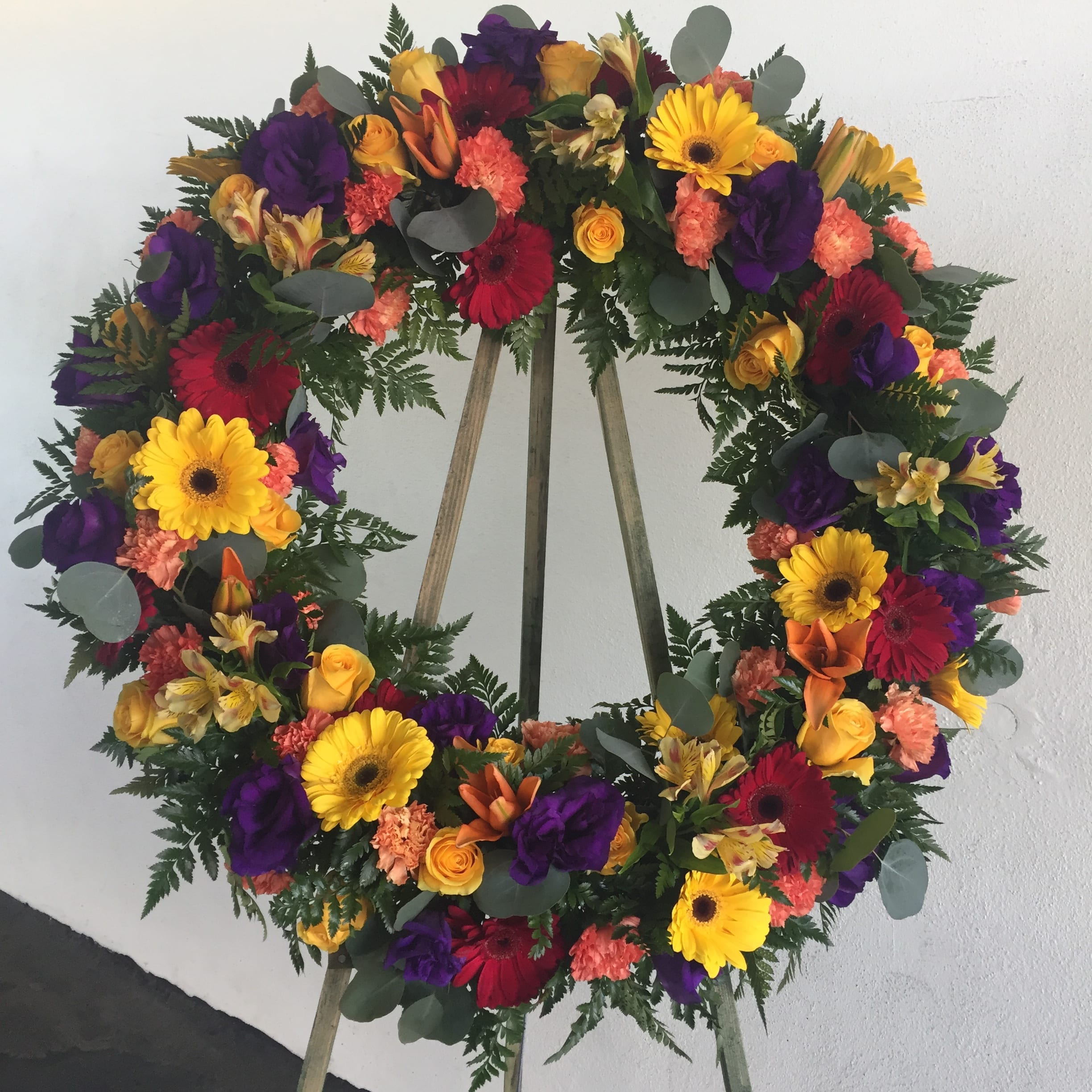 Jewel Tone Sympathy Wreath - Sympathy Wreath on a stand with a combination of flowers in jewel tones. Individual blooms will vary according to seasonality.