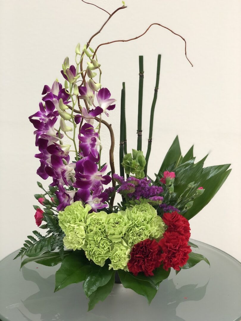 ZEN ARTRISTRY ZEN ARTRISTRY - "It’s artistic arrangements like this one that make flowers such an integral and beautiful ingredient in feng shui. A brilliant green container and exotic palm leaf provide the perfect backdrop for purple orchids and a mix of delightful tropical flowers. This gift takes artistry to new heights. Purple dendrobium orchids, green carnations, dark pink Sweet William, an emerald palm leaf and other tropical greens are arranged in a square kiwi-colored container. Perfect when you’ve got a yen to send Zen! Orientation: One-Sided All prices in USD ($)"