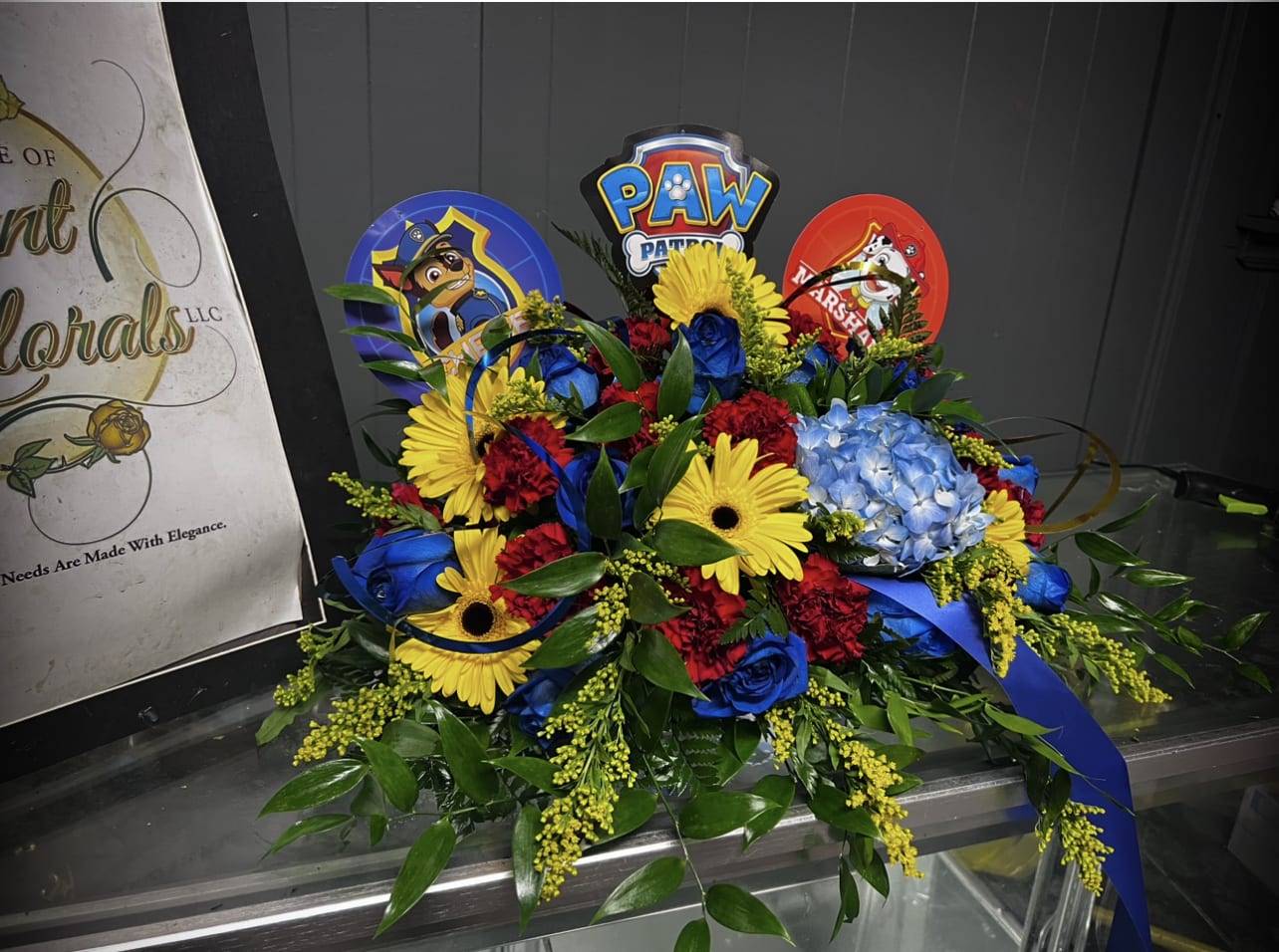 Child’s Casket Spray Themed Paw Patrol - This is an ideal arrangement for the services of a child. Bright bold themes colors of the show. Filled with Roses, Hydrangeas, Carnations, Italian Ruscus Leaves and much more!