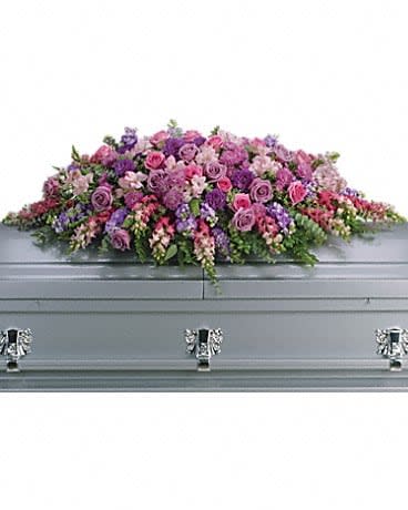 Lavender Tribute Casket Spray - Like a heartfelt embrace, this beautiful casket spray delivers comfort and love in an extraordinary way. A wonderful array of lavender and pink flowers with just the right amount of greenery is a lovely way to pay tribute to someone who will always be with you in heart, mind and spirit. Lovely lavender and pink roses, snapdragons, alstroemeria, chrysanthemums, fern, eucalyptus and more create this tribute that is overflowing with grace and love.