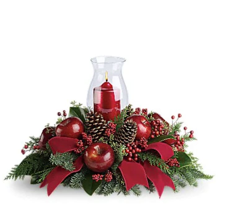 Merry Magnificence - Shiny red apples and all kinds of holiday flowers and features make this centerpiece a very tasteful gift. The beautiful hurricane glass and ruby red pillar candle complete the stylish arrangement! Brilliant red roses, spray roses, berries and apples are delivered with an elegant hurricane candle, pinecones, winter greens and a stunning red velvet ribbon. It brings a lot of elegance to the table!   Orientation : All-Around  All prices in USD ($)  Standard  T121-1A  Deluxe  T121-1B  Premium  T121-1C